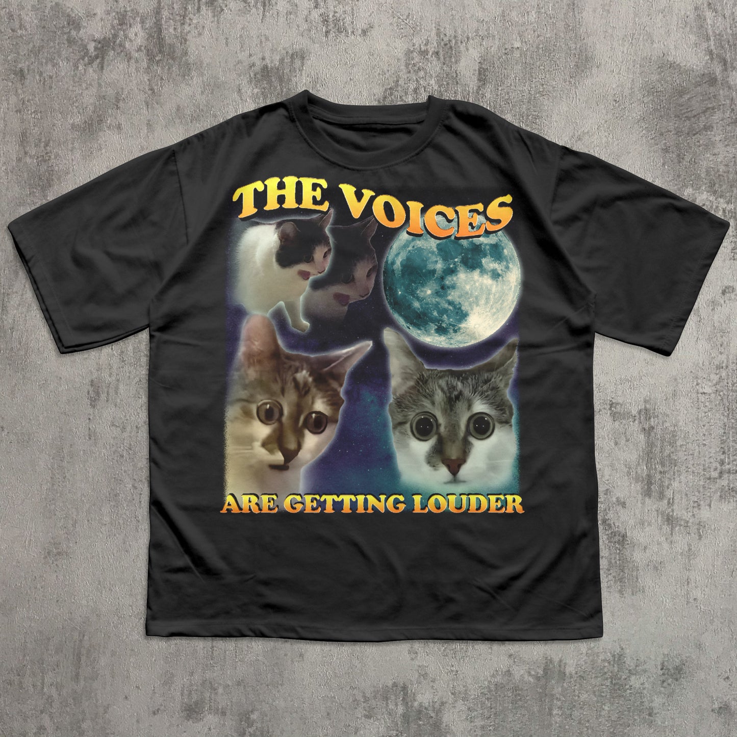Black t-shirt with cat graphic and text 'The Voices Are Getting Louder' on a textured gray background
