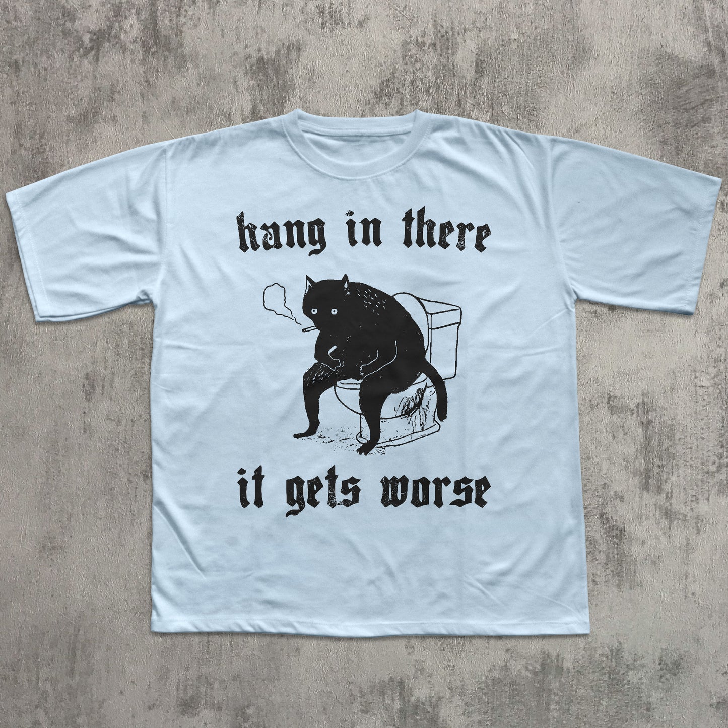 Light blue t-shirt with black graphic of a cat and text on a textured gray background