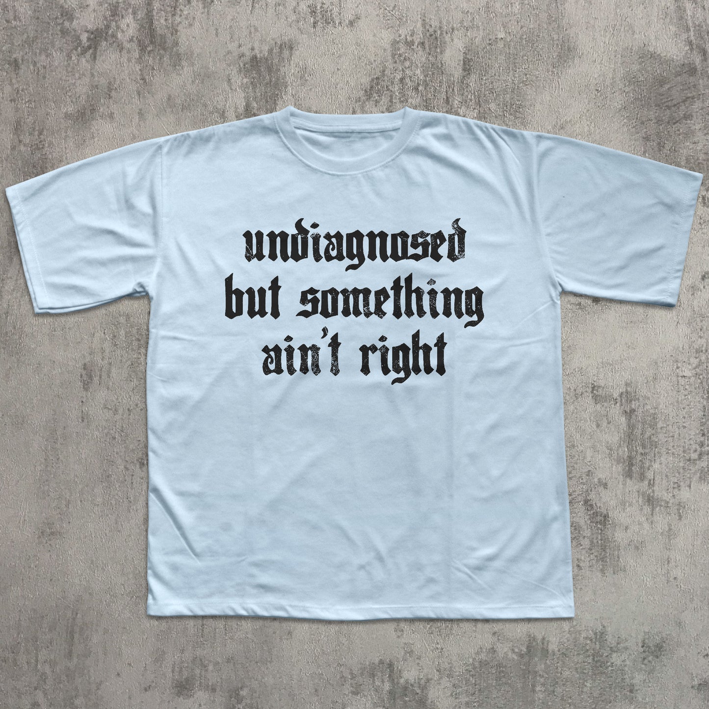 Light blue t-shirt with black text on a textured gray background