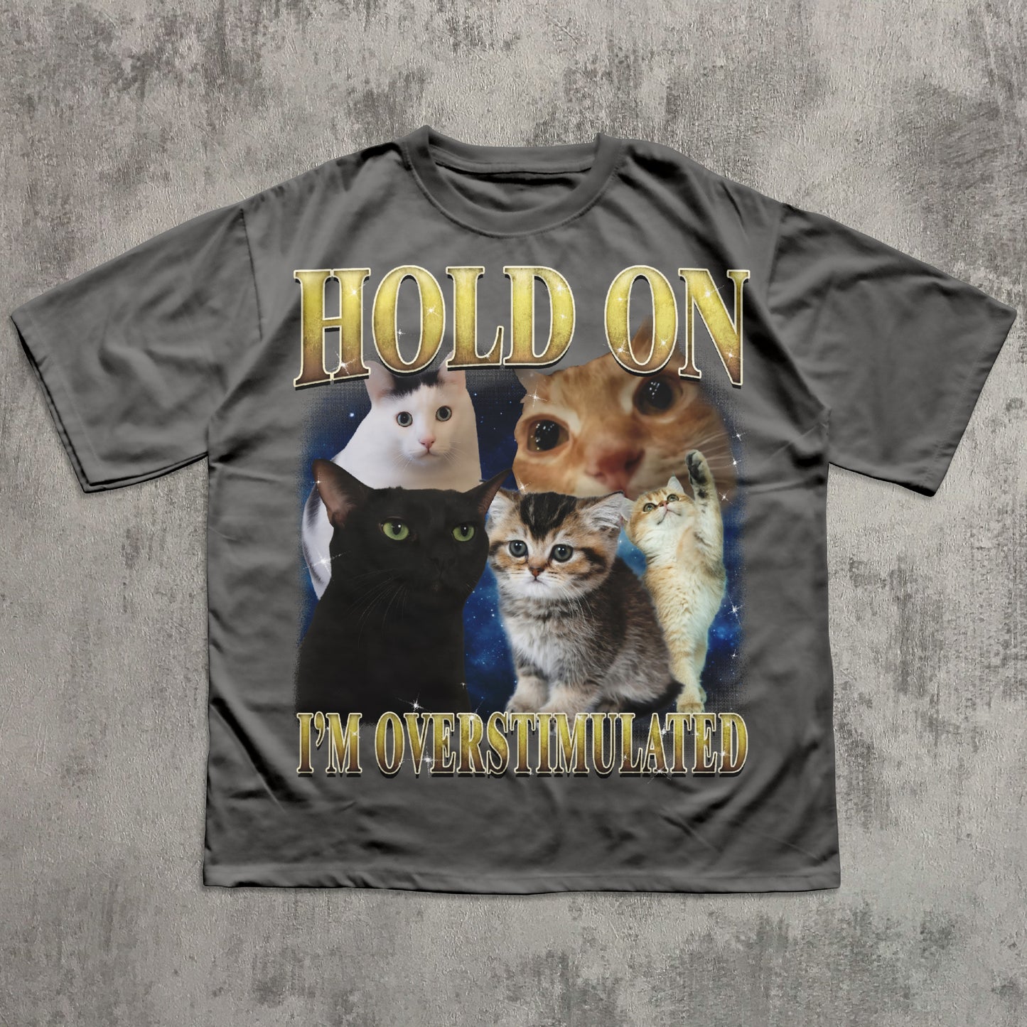 Gray t-shirt with cat graphic and text 'Hold on I'm overstimulated' on a textured gray background