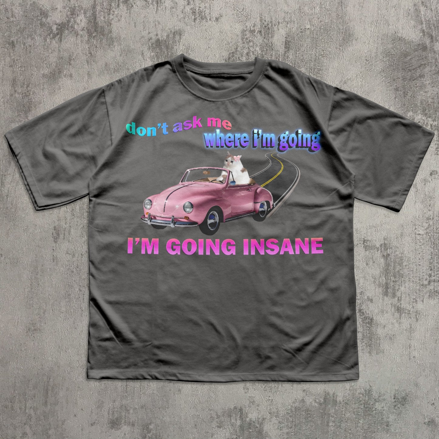Funny cat meme gray t-shirt with a pink car graphic and text on a concrete surface