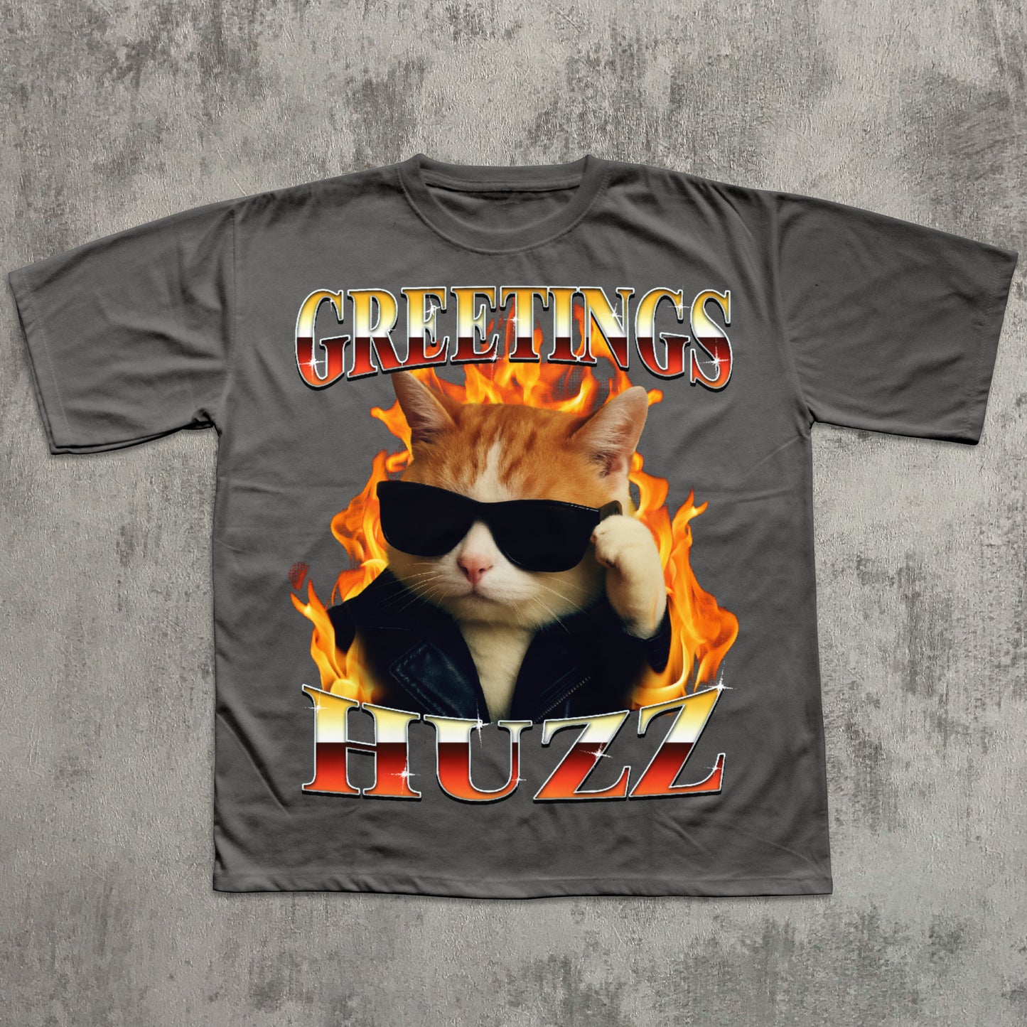 Gray t-shirt with a cat graphic and 'Greetings HUZZ' text on a concrete surface