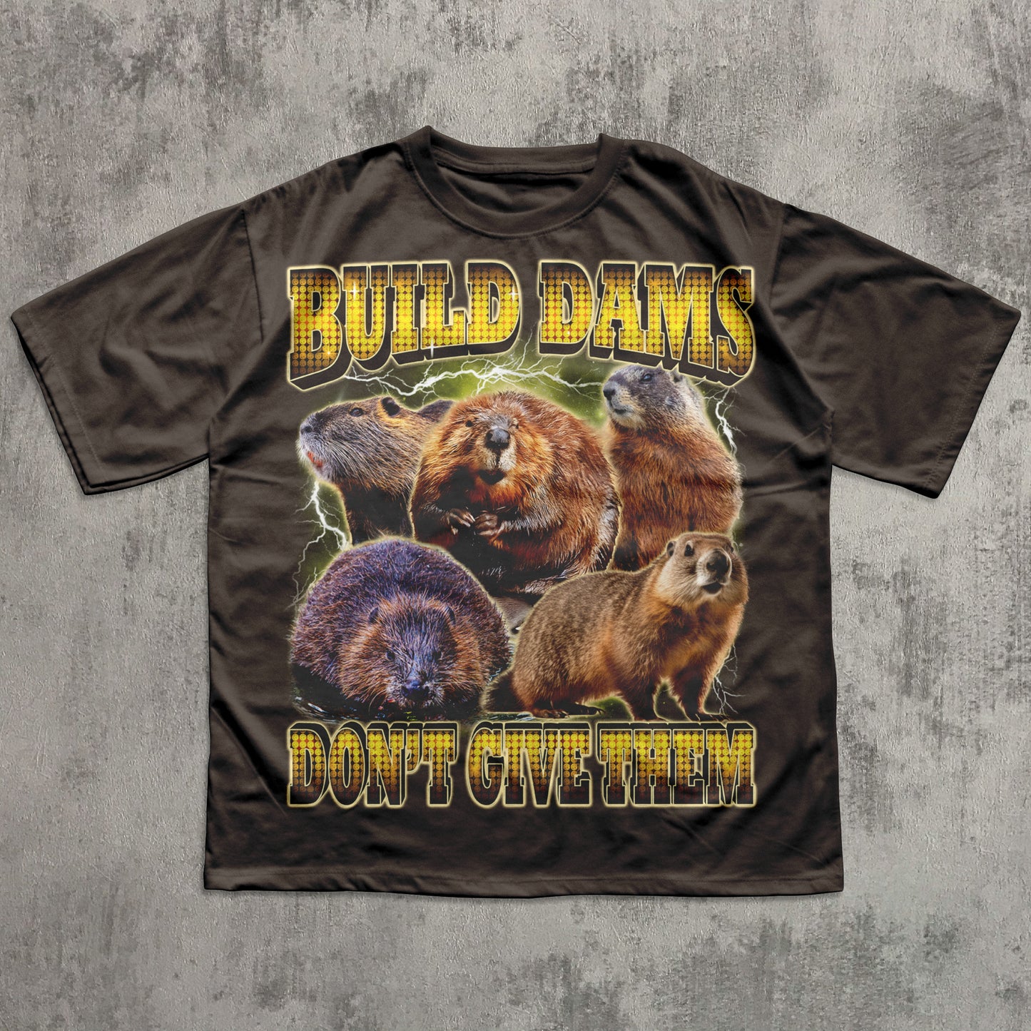 Brown T-shirt featuring a collage of beavers surrounded by lightning effects with bold yellow lettering that says ‘Build Dams, Don’t Give Them