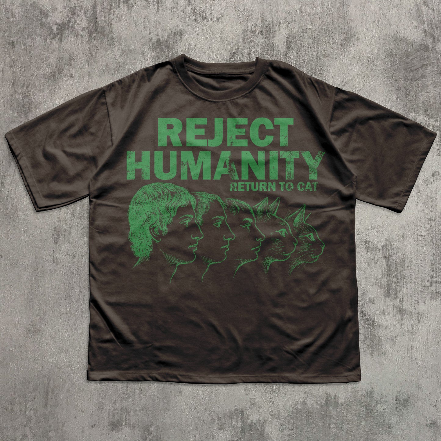 Brown t-shirt with green graphic and text 'REJECT HUMANITY RETURN TO CAT' on a textured gray background
