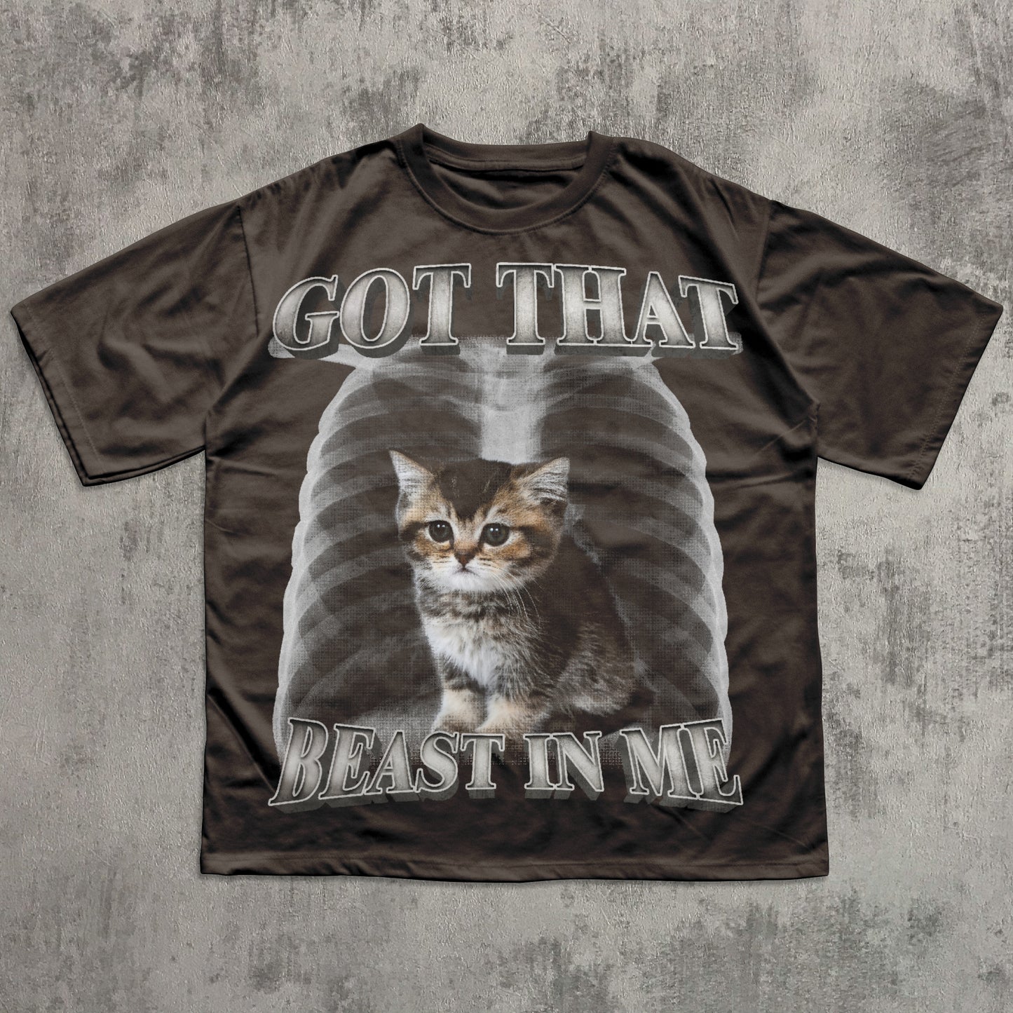 Brown t-shirt with a graphic of a cat and text 'GOT THAT BEAST IN ME' on a textured gray background