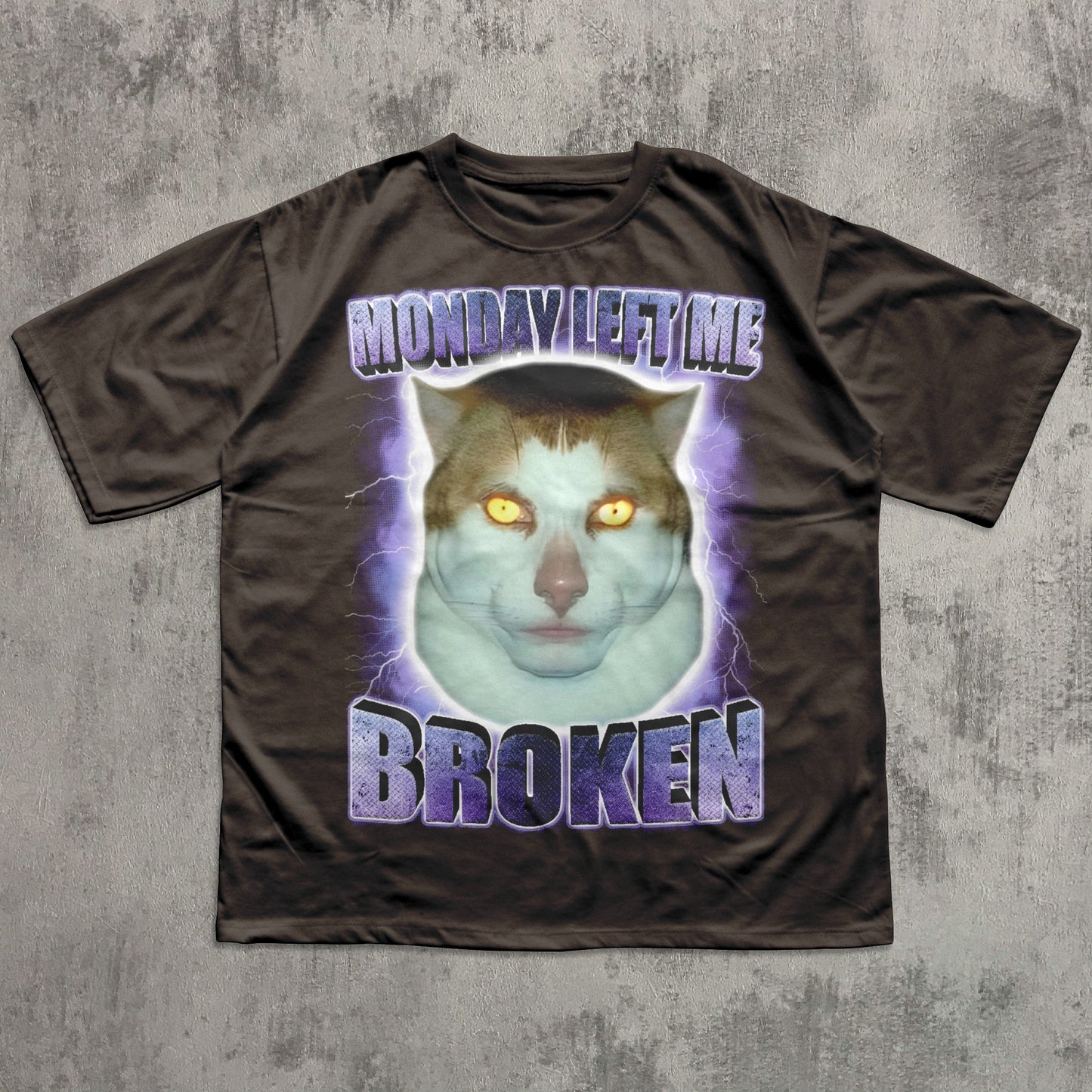Brown funny t-shirt with a graphic of a cat and text 'Monday Left Me Broken' on a textured gray background