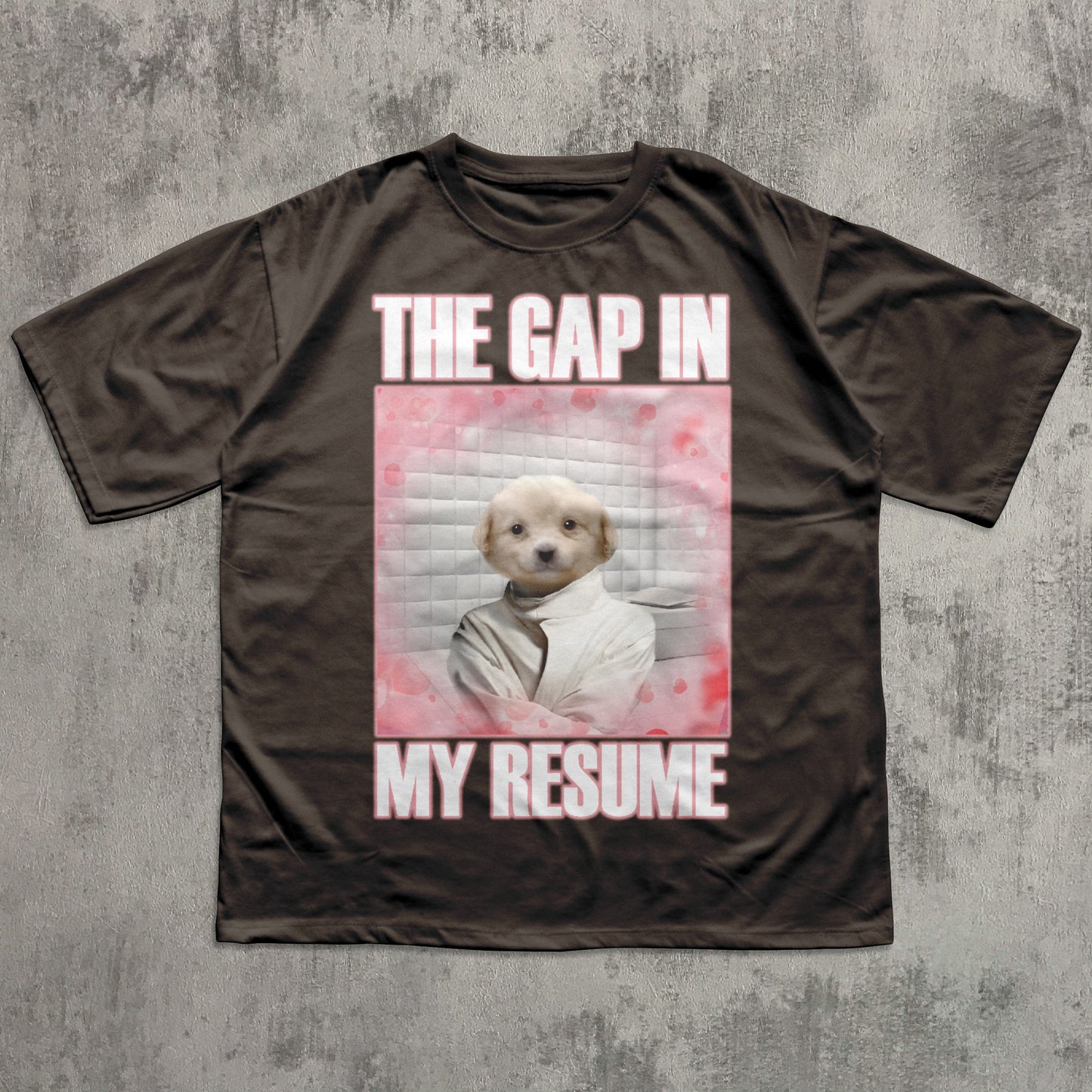 Brown t-shirt with a graphic of a dog and text 'The gap in my resume' on a textured gray background