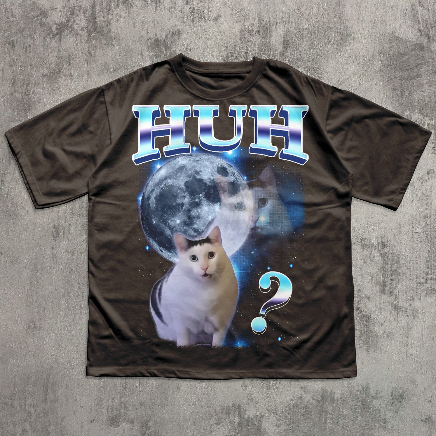 Brown t-shirt with a cat graphic and 'HUH?' text on a textured gray background