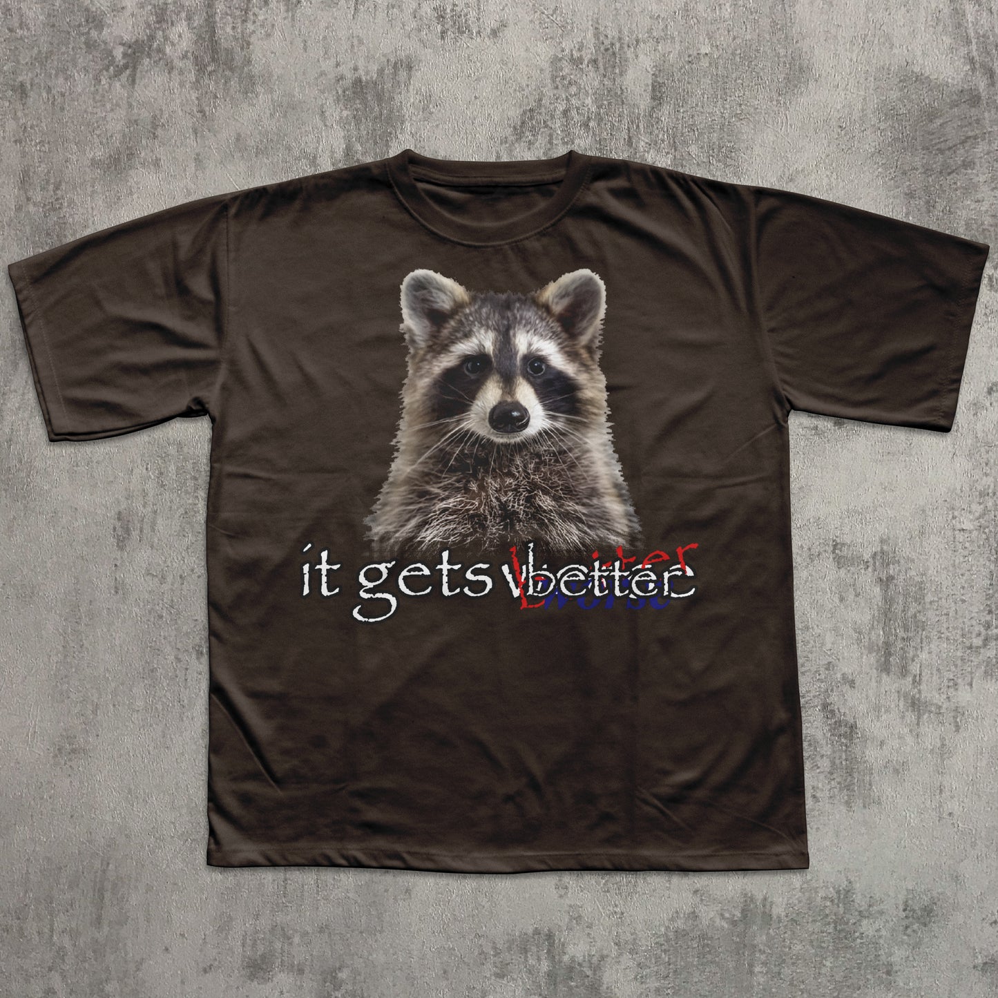 Brown t-shirt with a raccoon graphic and text 'it gets better' on a textured gray background