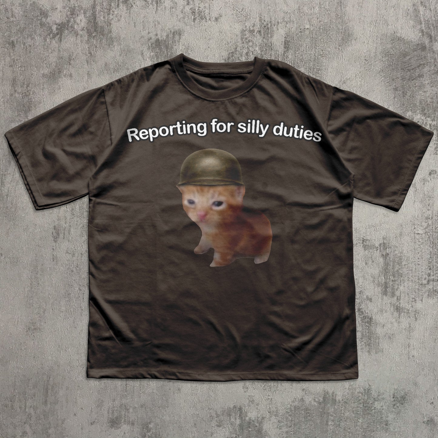 Brown t-shirt with a kitten wearing a helmet and text 'Reporting for silly duties' on a textured gray background