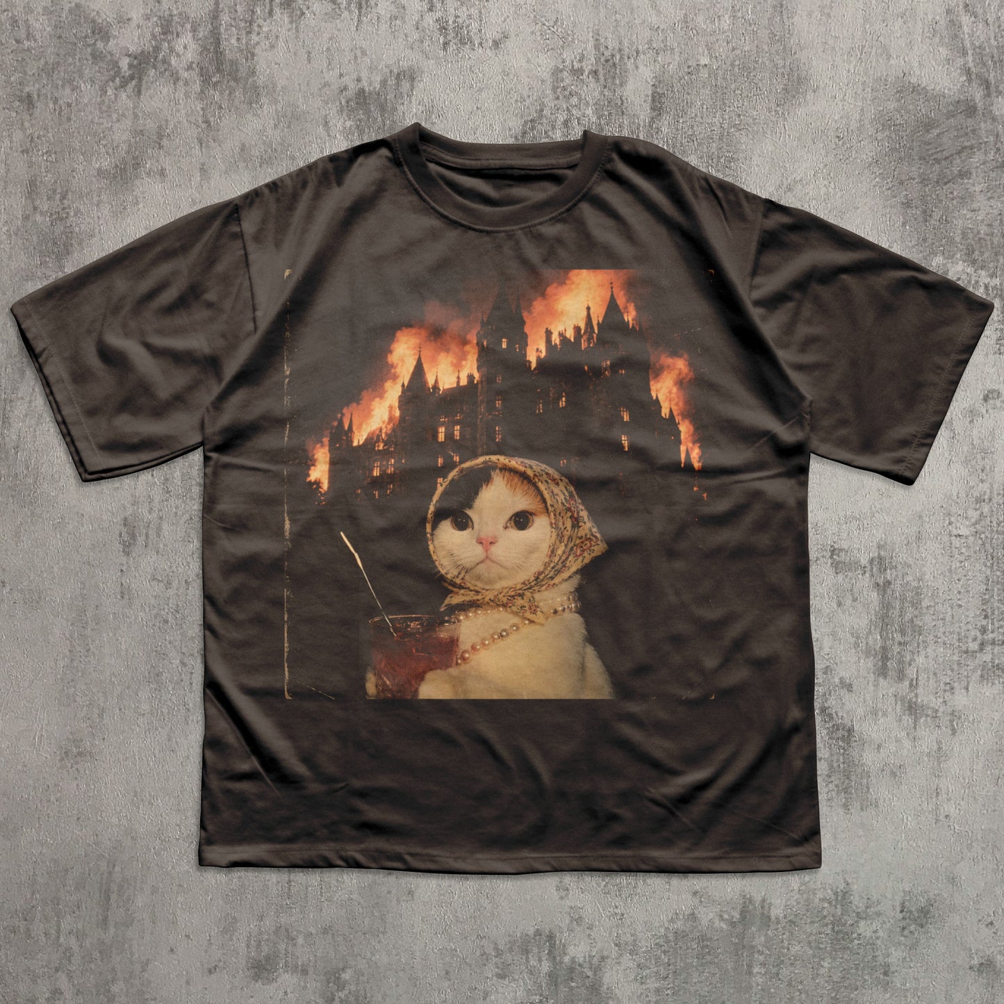Brown t-shirt with a graphic of a cat in a hood and flames on a textured gray background