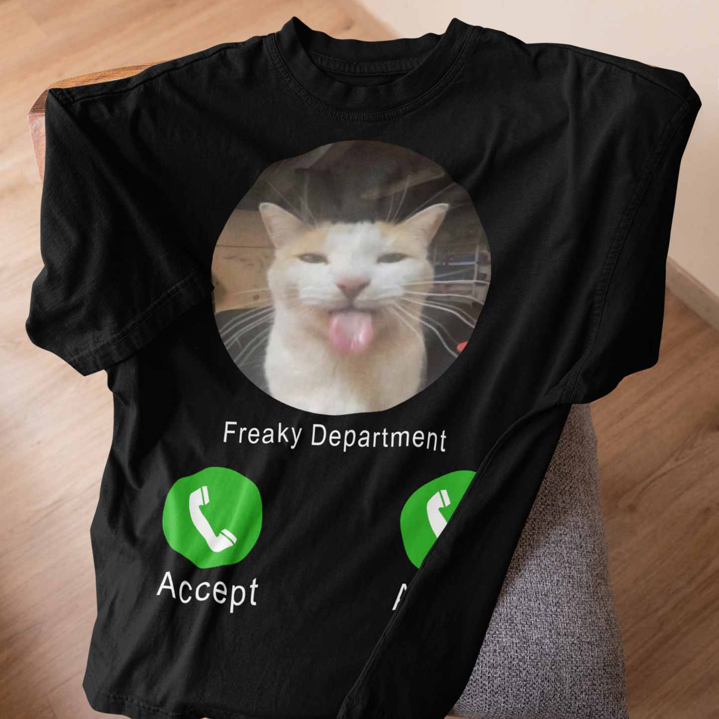 Black t-shirt with a cat graphic and 'Freaky Department Accept' text on a wooden surface.