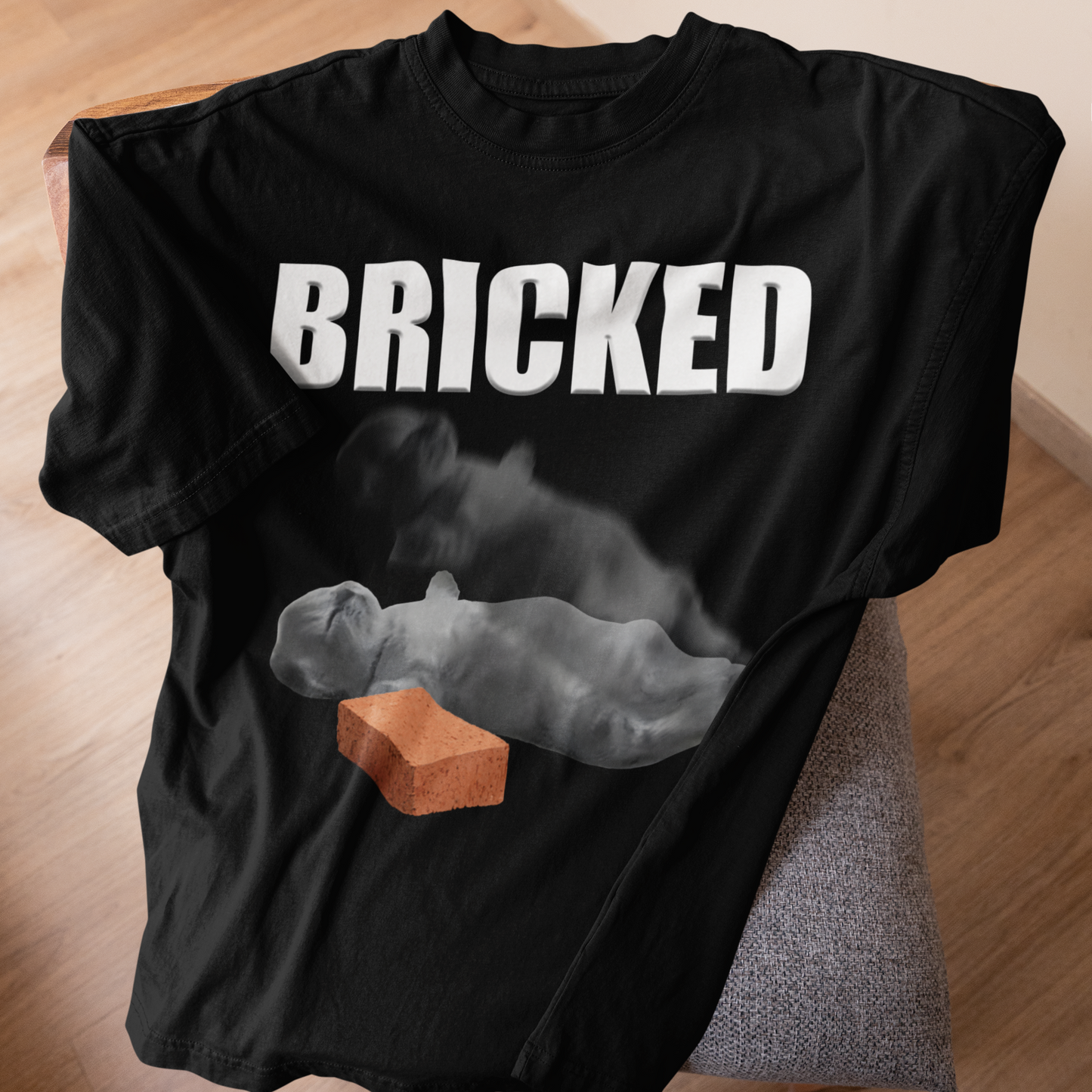 Black t-shirt with 'BRICKED' text and graphic of a Cat and brick on a wooden surface.
