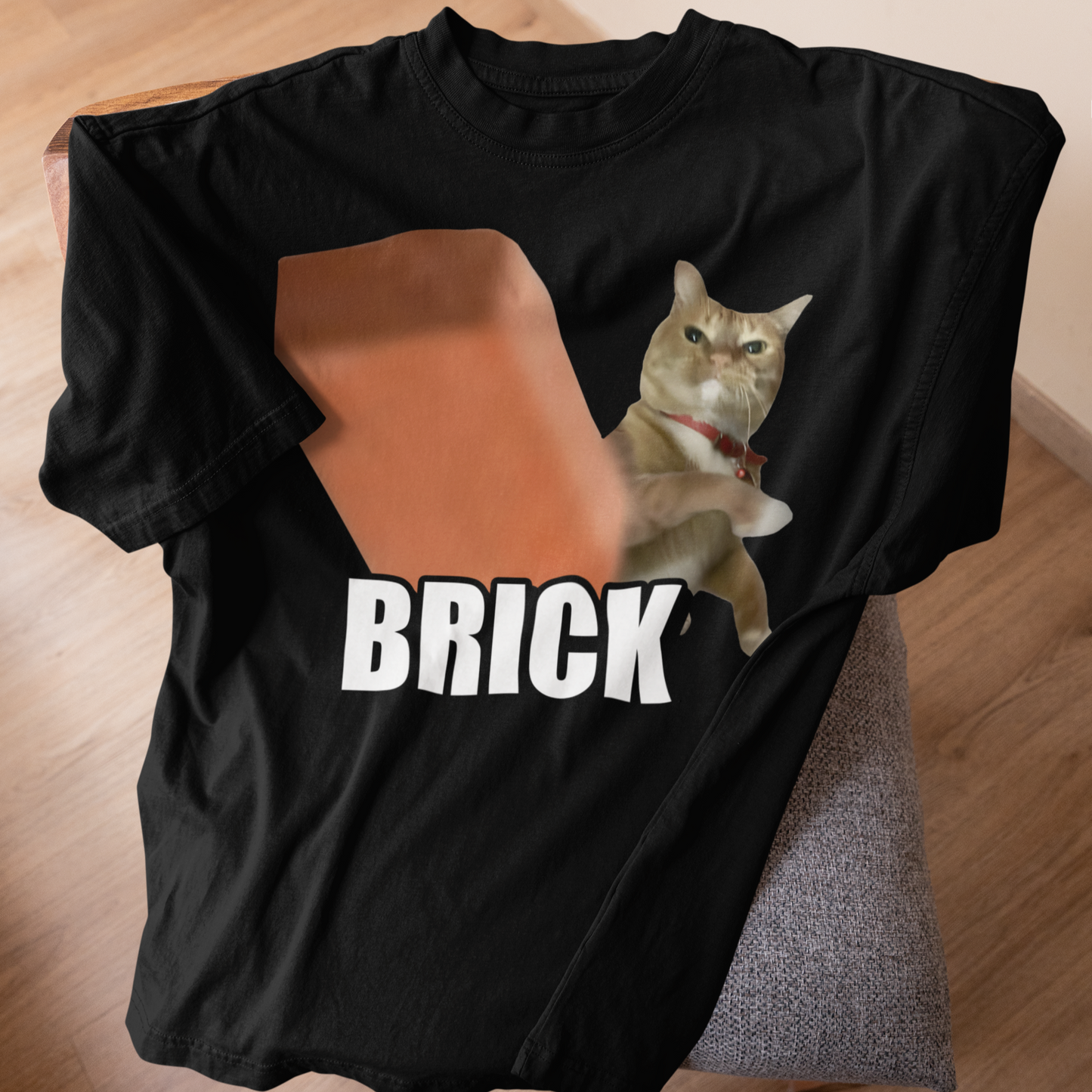 Black t-shirt with a cat graphic and 'BRICK' text on a wooden surface