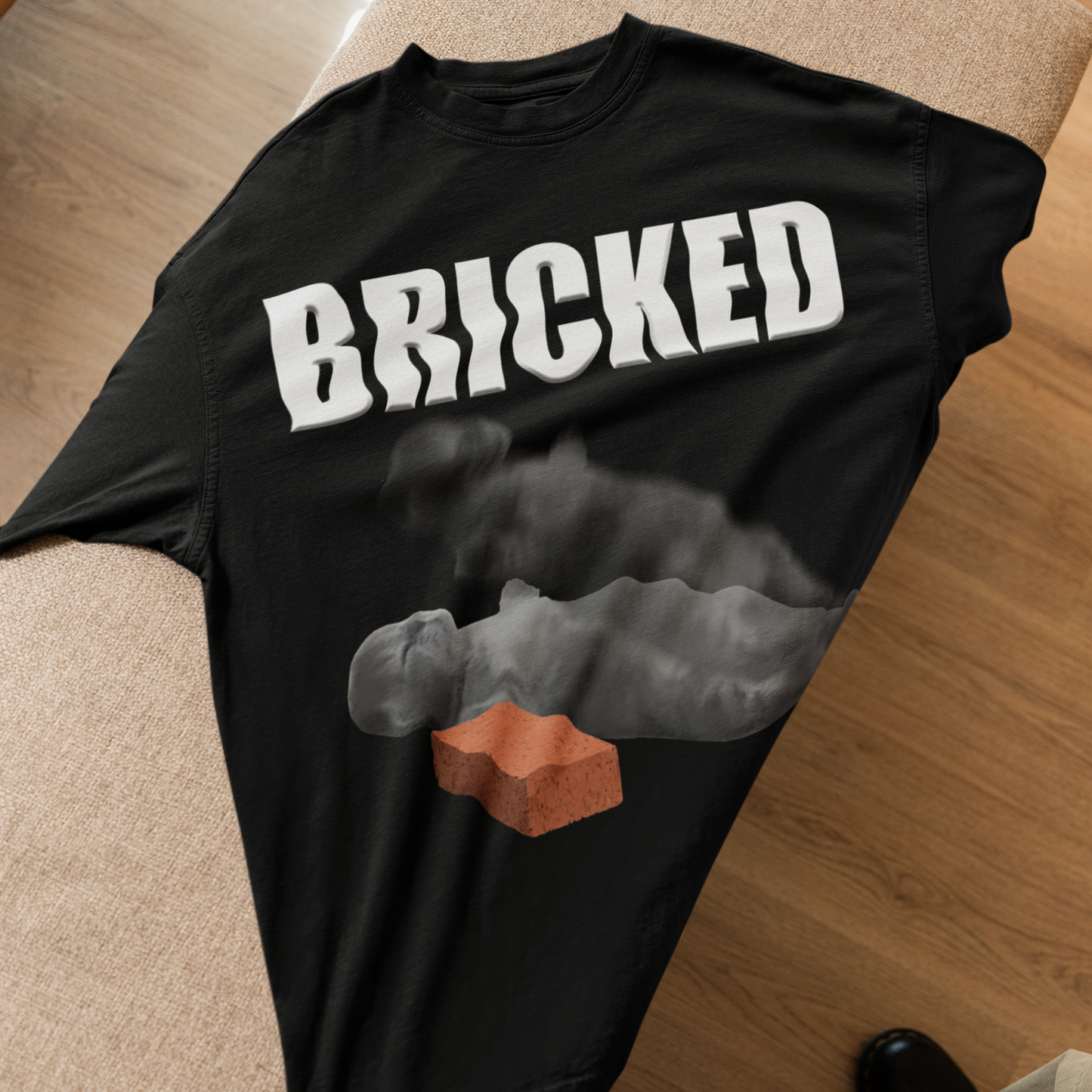 Black t-shirt with 'BRICKED' text and brick graphic on a wooden floor.