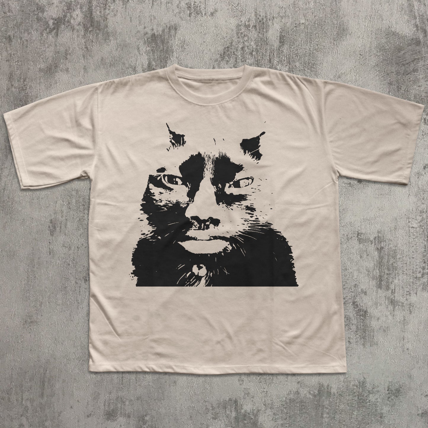 Beige t-shirt with a black cat graphic on a textured gray background