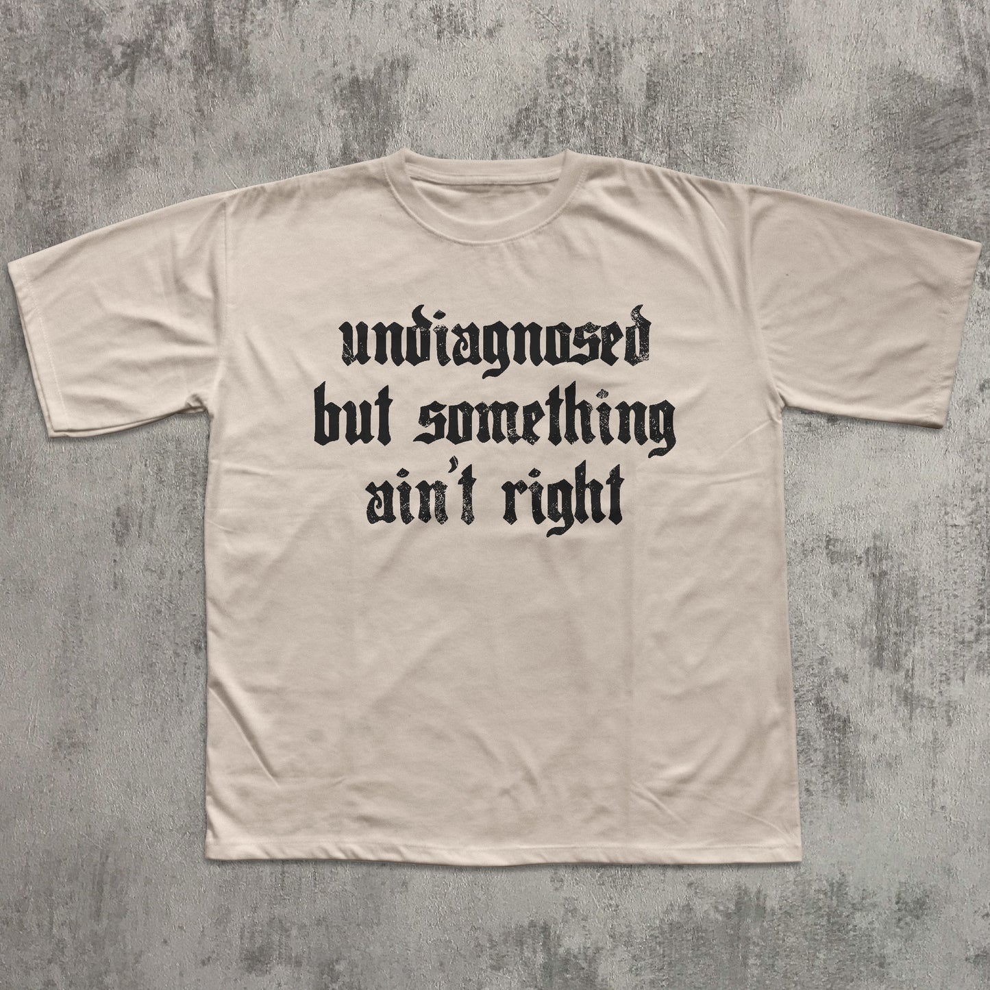 Beige t-shirt with black text on a textured gray background