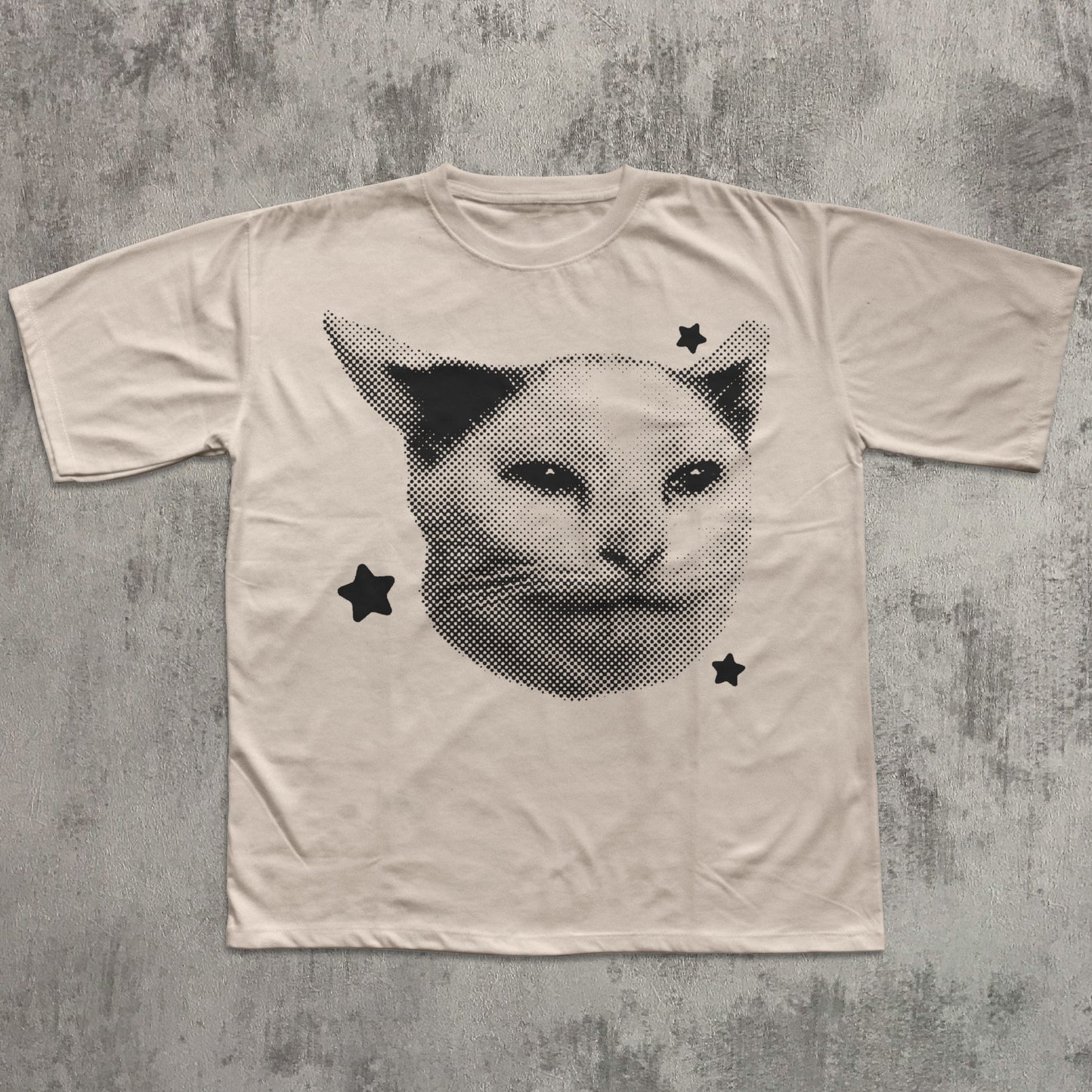 Beige t-shirt with a cat face design on a textured gray background