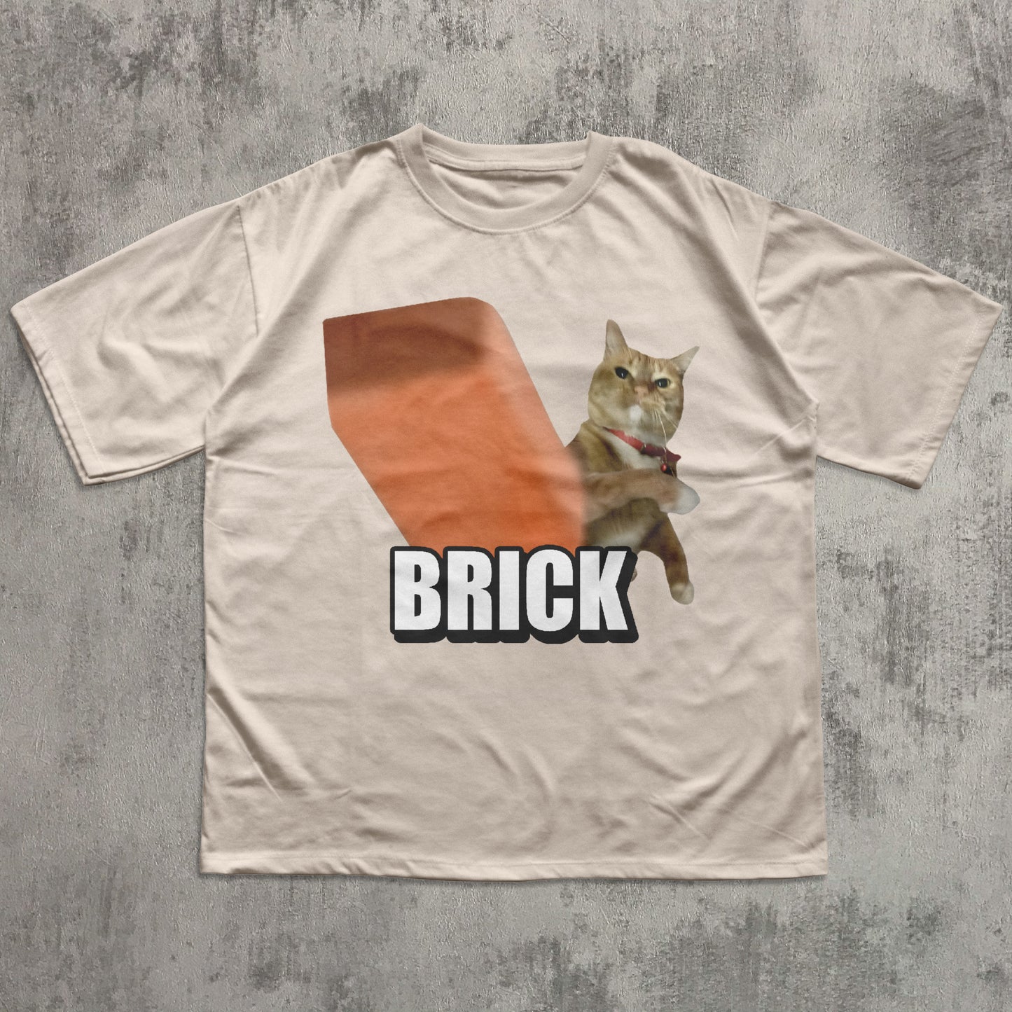 Beige t-shirt with a cat graphic and 'BRICK' text on a textured gray background