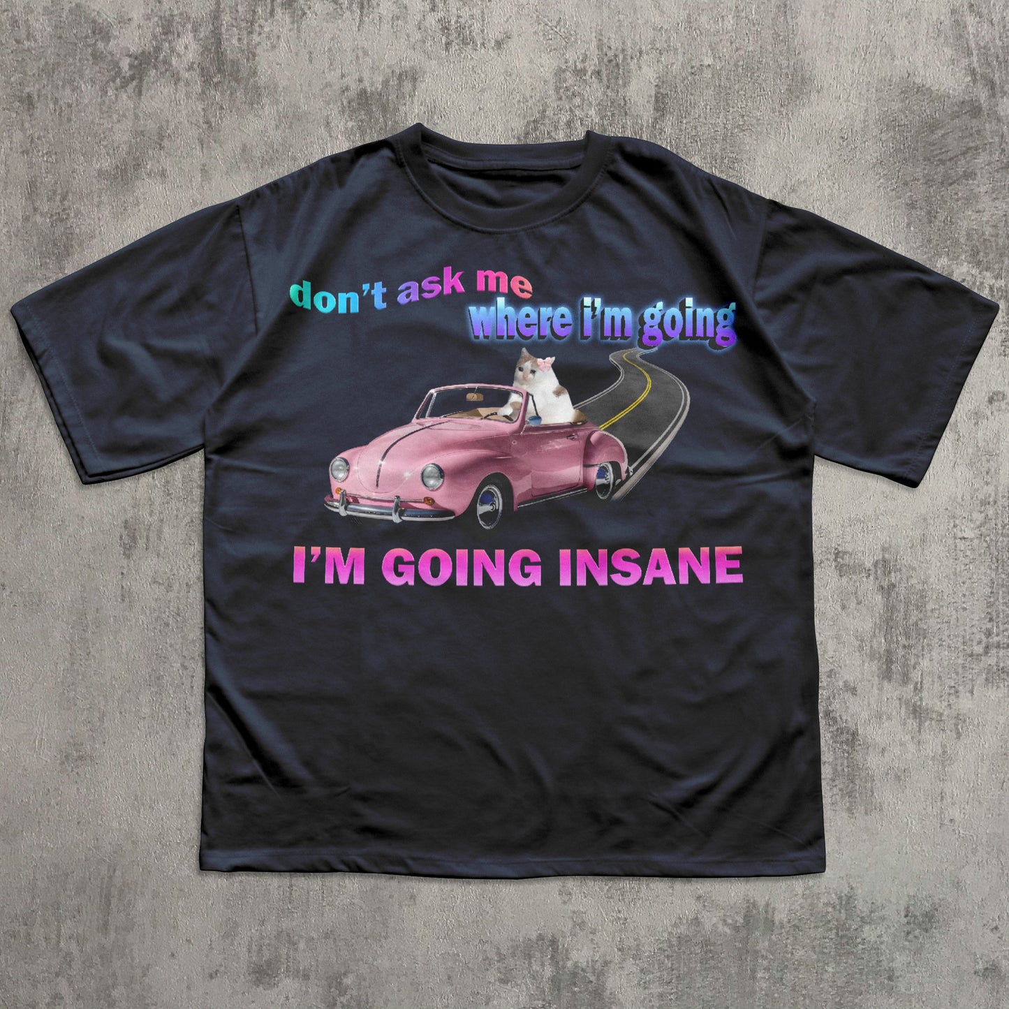 Funny cat meme navy t-shirt with a pink car graphic and text on a concrete surface