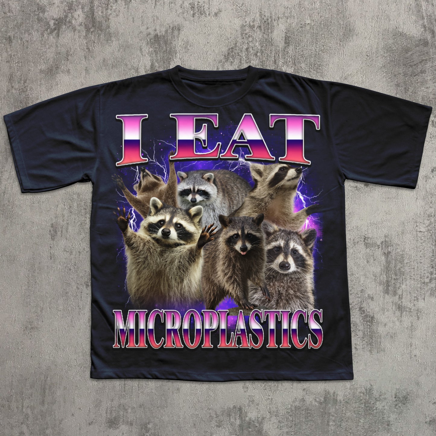 Black t-shirt with raccoon graphic and 'I Eat Microplastics' text on a textured gray background