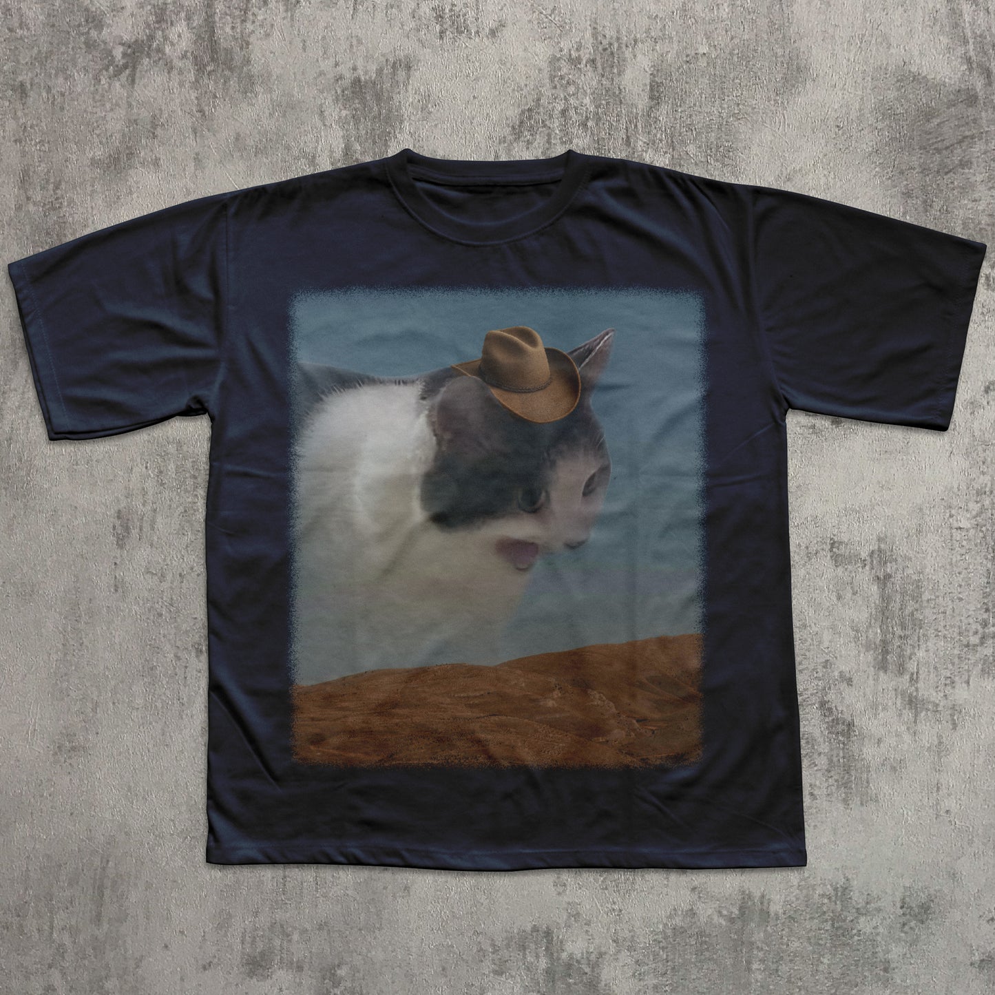 Black t-shirt with a printed design of a cat wearing a cowboy hat on a textured gray background