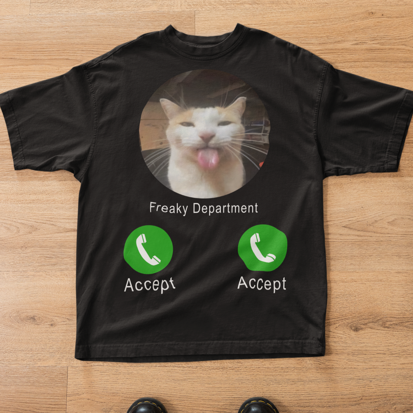 Black t-shirt with a cat graphic and text on a wooden surface