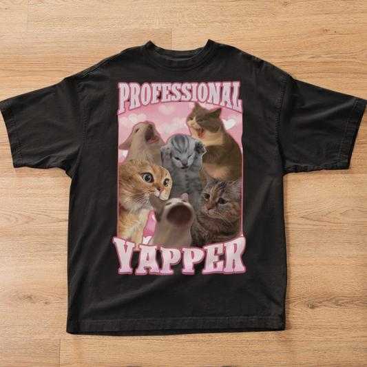 Black t-shirt with a graphic of cats and the text 'Professional Yapper' on a wooden surface.