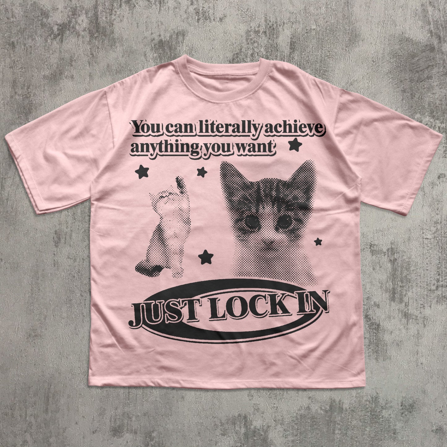 Pink t-shirt with a cat graphic and motivational text on a textured gray background