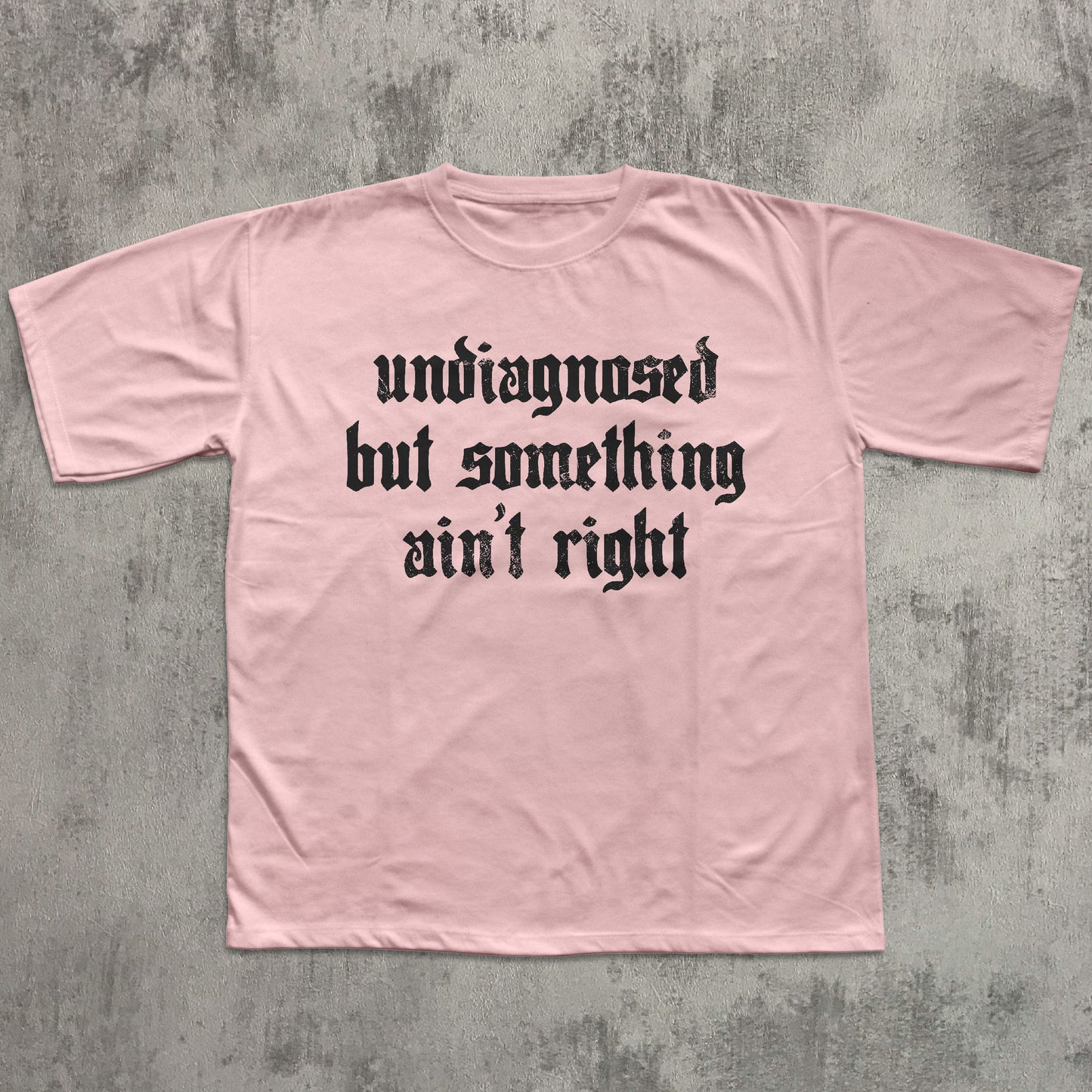 Pink t-shirt with black text on a gray concrete background