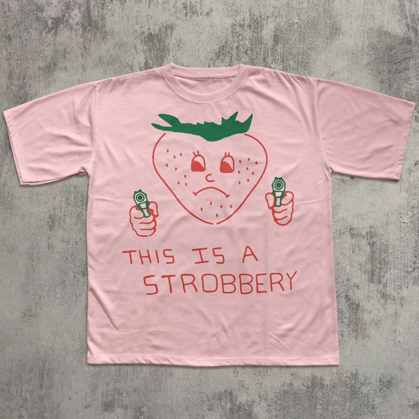 Pink t-shirt with a strawberry graphic and text on a gray concrete background