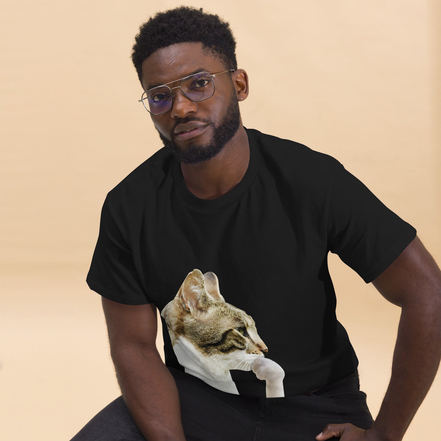 Man wearing a black t-shirt with a cat graphic on a beige background