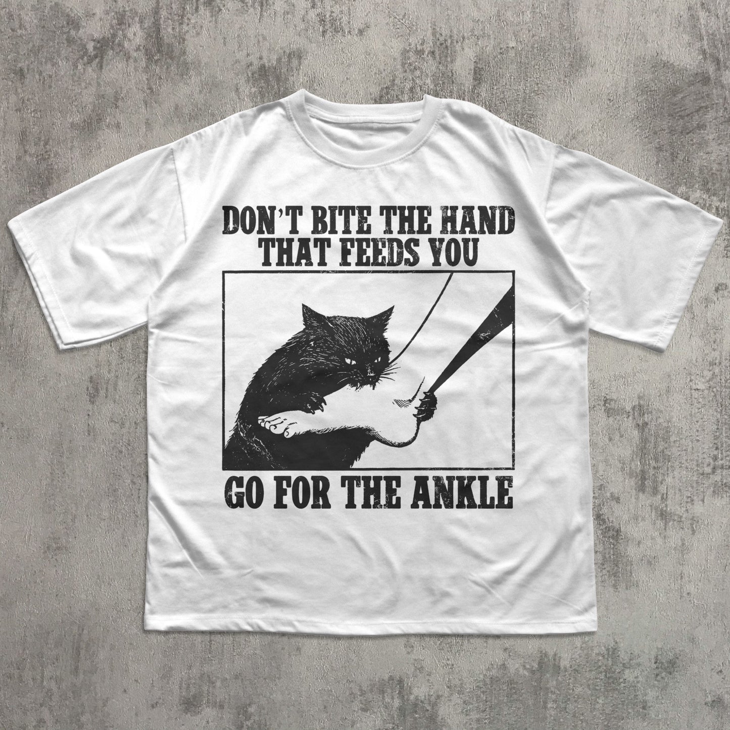 White t-shirt with black graphic and text on a gray concrete background