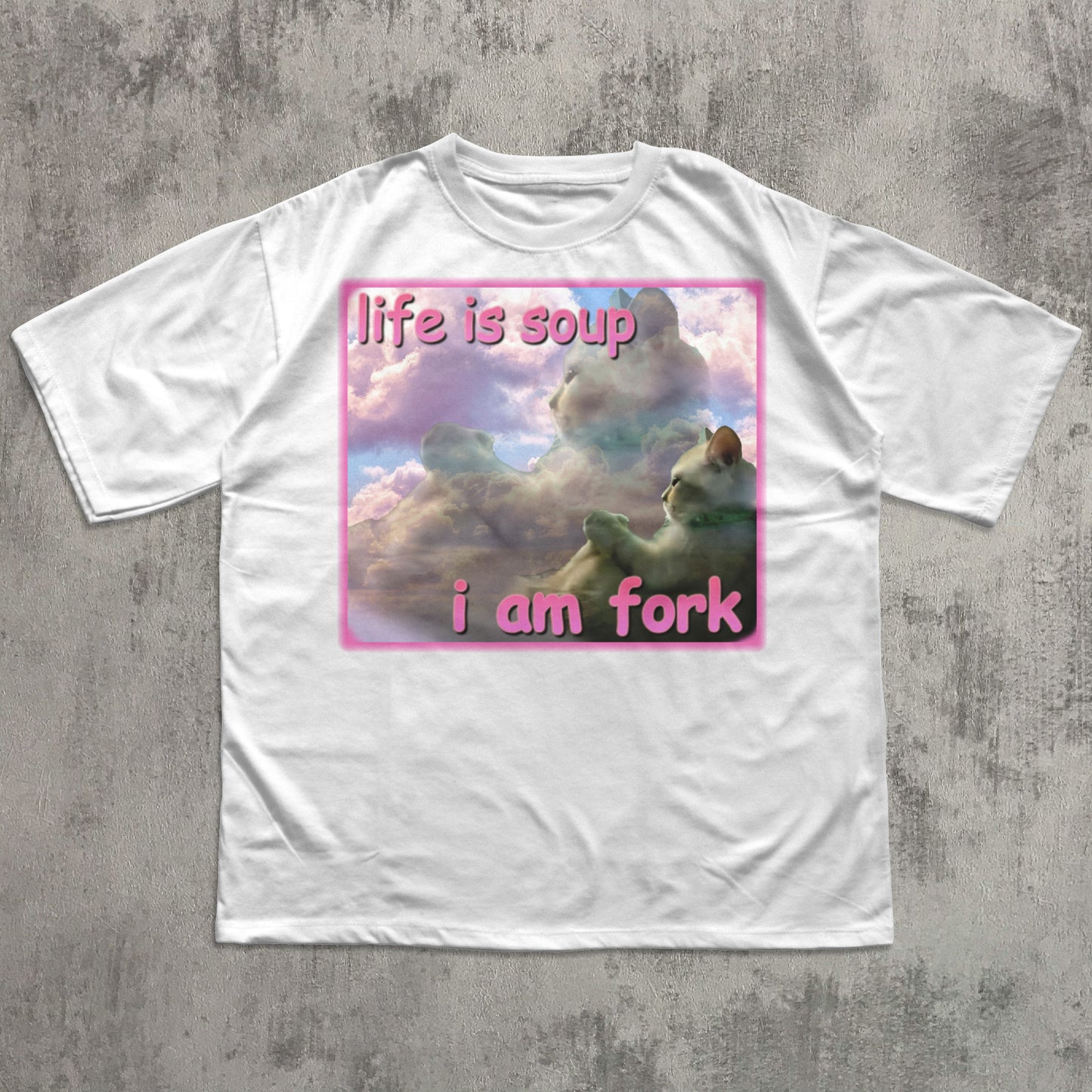 White t-shirt with a graphic design featuring cats and text on a concrete surface