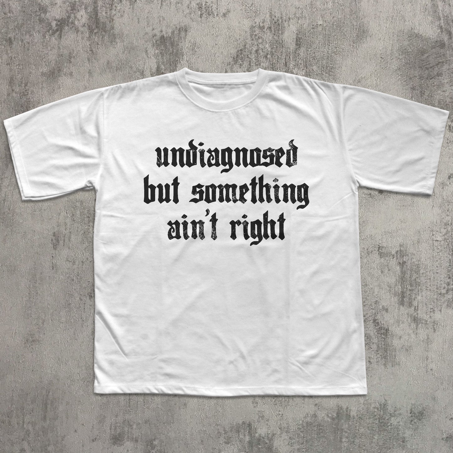 White t-shirt with black text on a gray concrete background