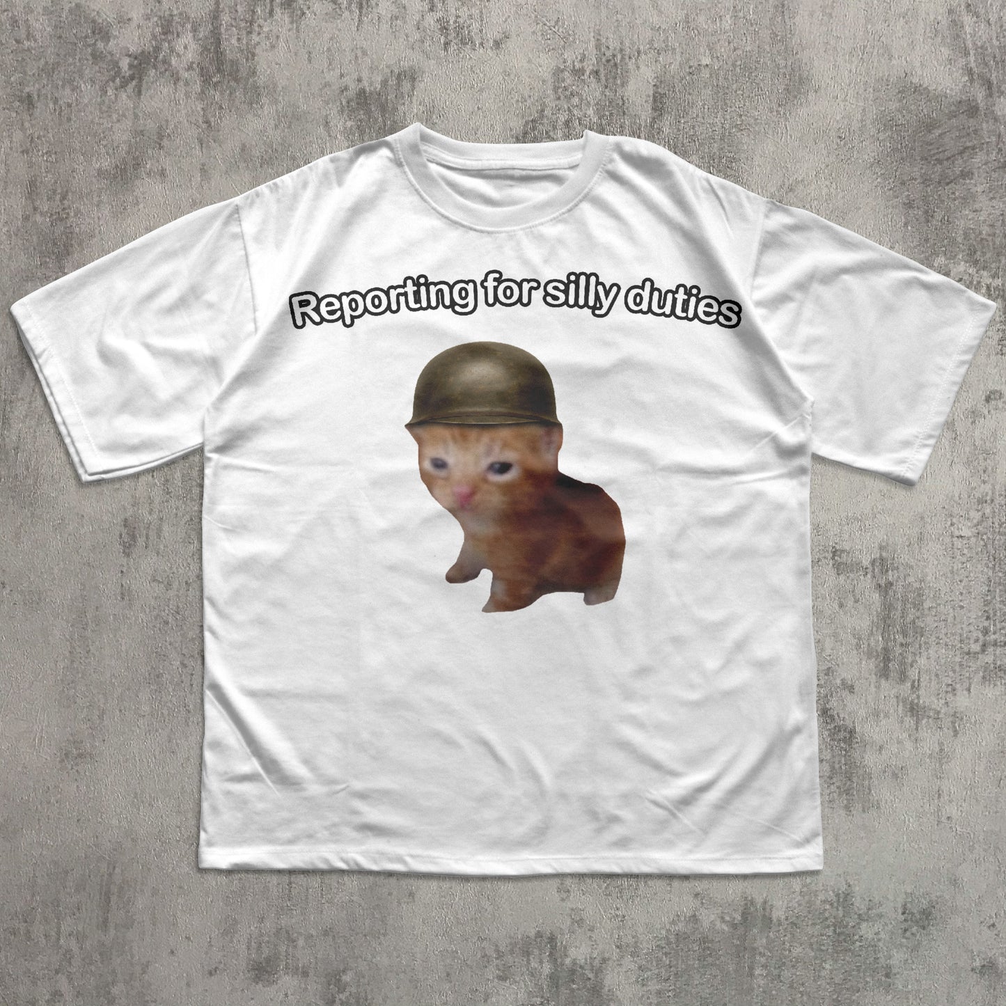 White t-shirt with a Cat wearing a helmet and text 'Reporting for silly duties' on a concrete surface.