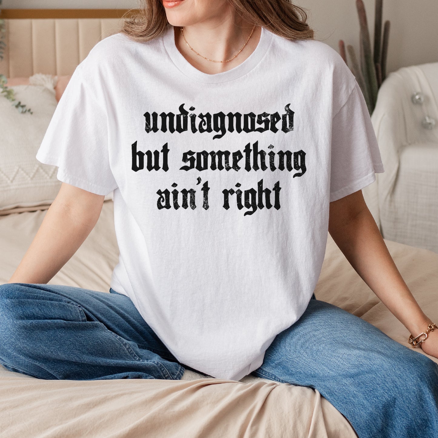 Person wearing a white t-shirt with text sitting on a couch.