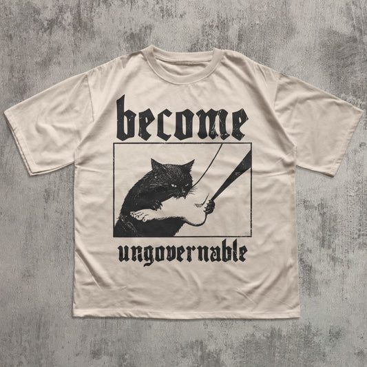 Beige t-shirt with black graphic of a cat holding a sword and text 'become ungovernable' on a textured gray background