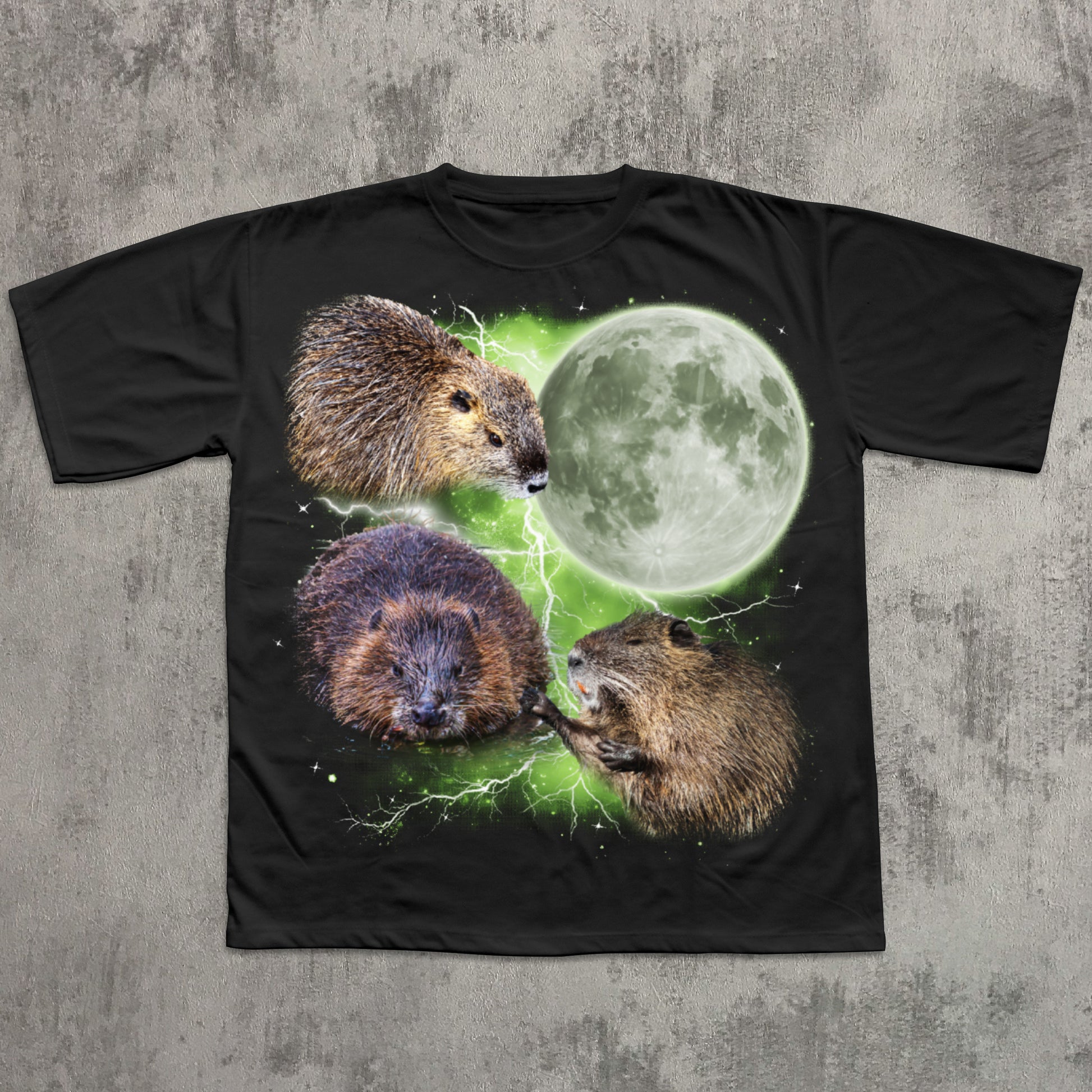 Black graphic T-shirt featuring three realistic beavers arranged around a glowing full moon with green lightning effects in the background.