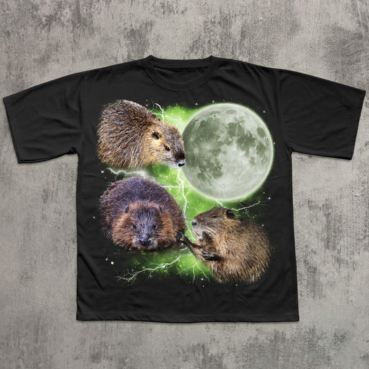 Black graphic T-shirt featuring three realistic beavers arranged around a glowing full moon with green lightning effects in the background.