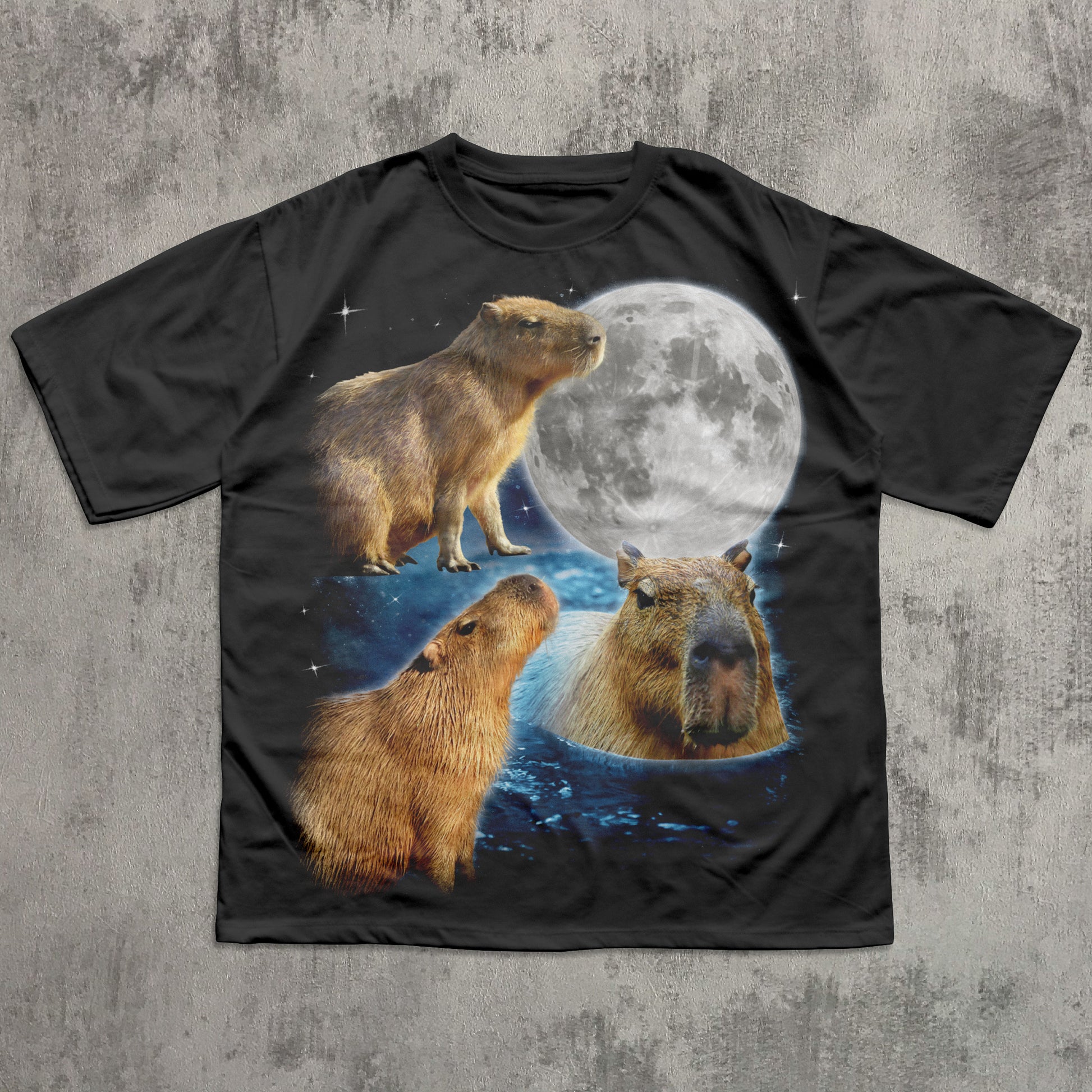 Black t-shirt with capybara design and moon on a textured gray background