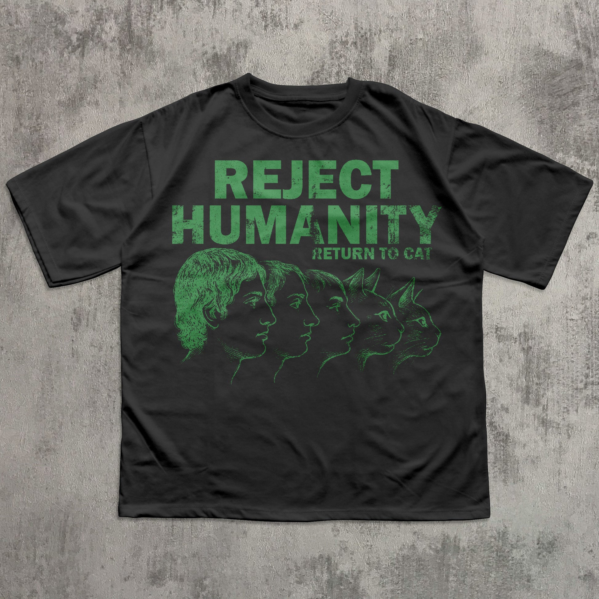 Black t-shirt with green graphic and text 'REJECT HUMANITY RETURN TO CAT' on a textured gray background