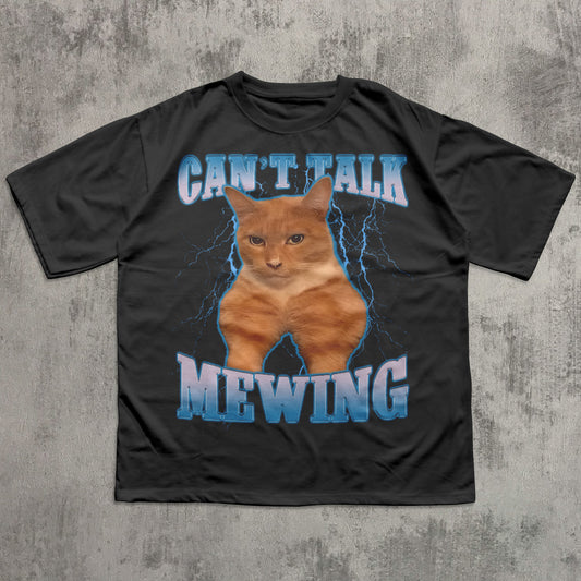 funny Black t-shirt with a cat graphic and text 'CAN'T TALK MEOWING' on a textured gray background