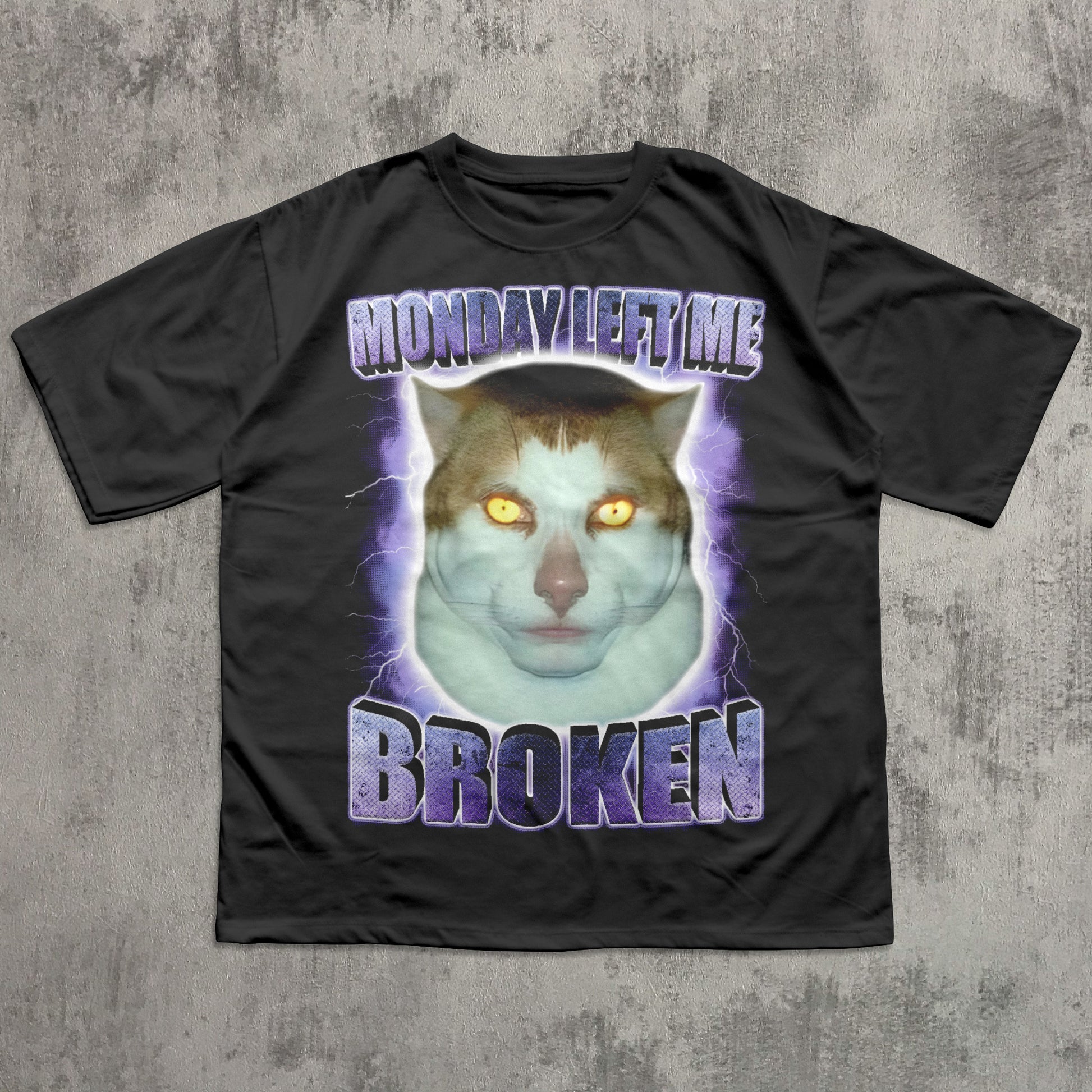 Black funny t-shirt with a graphic of a cat and text 'Monday Left Me Broken' on a textured gray background