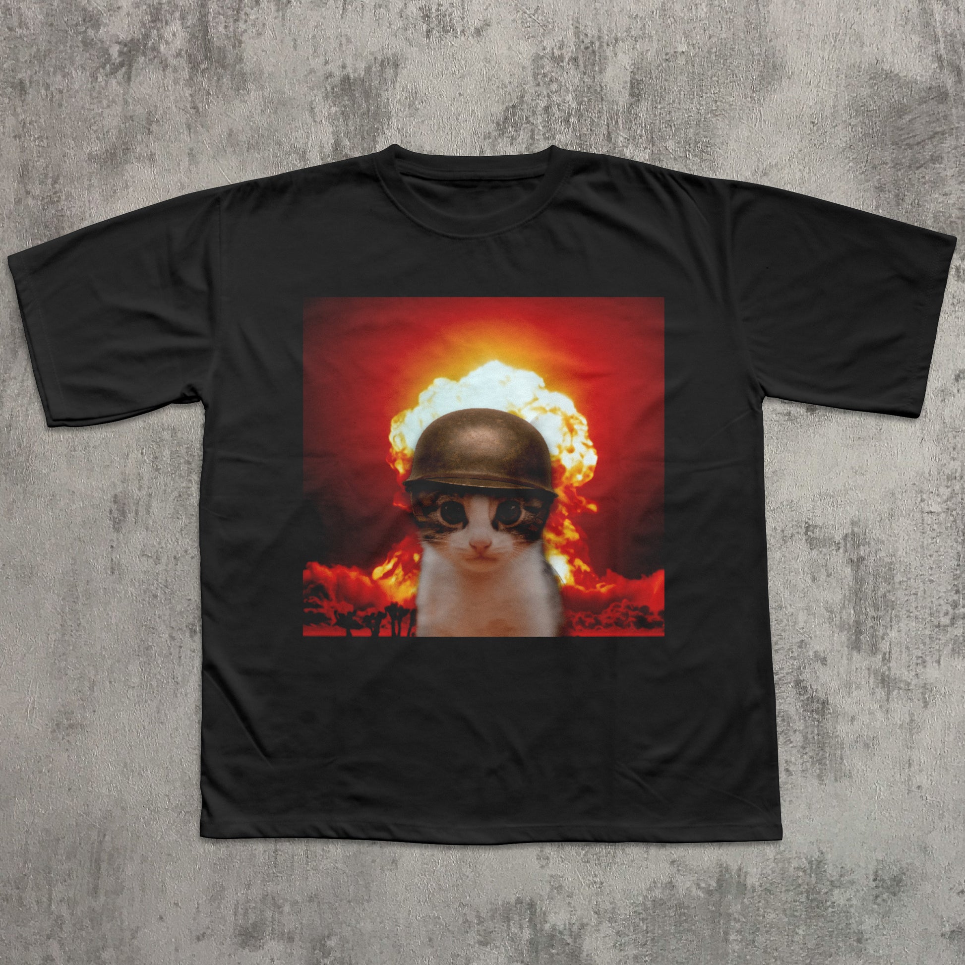 Black t-shirt with a graphic of a cat wearing sunglasses and a helmet amidst an explosion on a textured gray background.