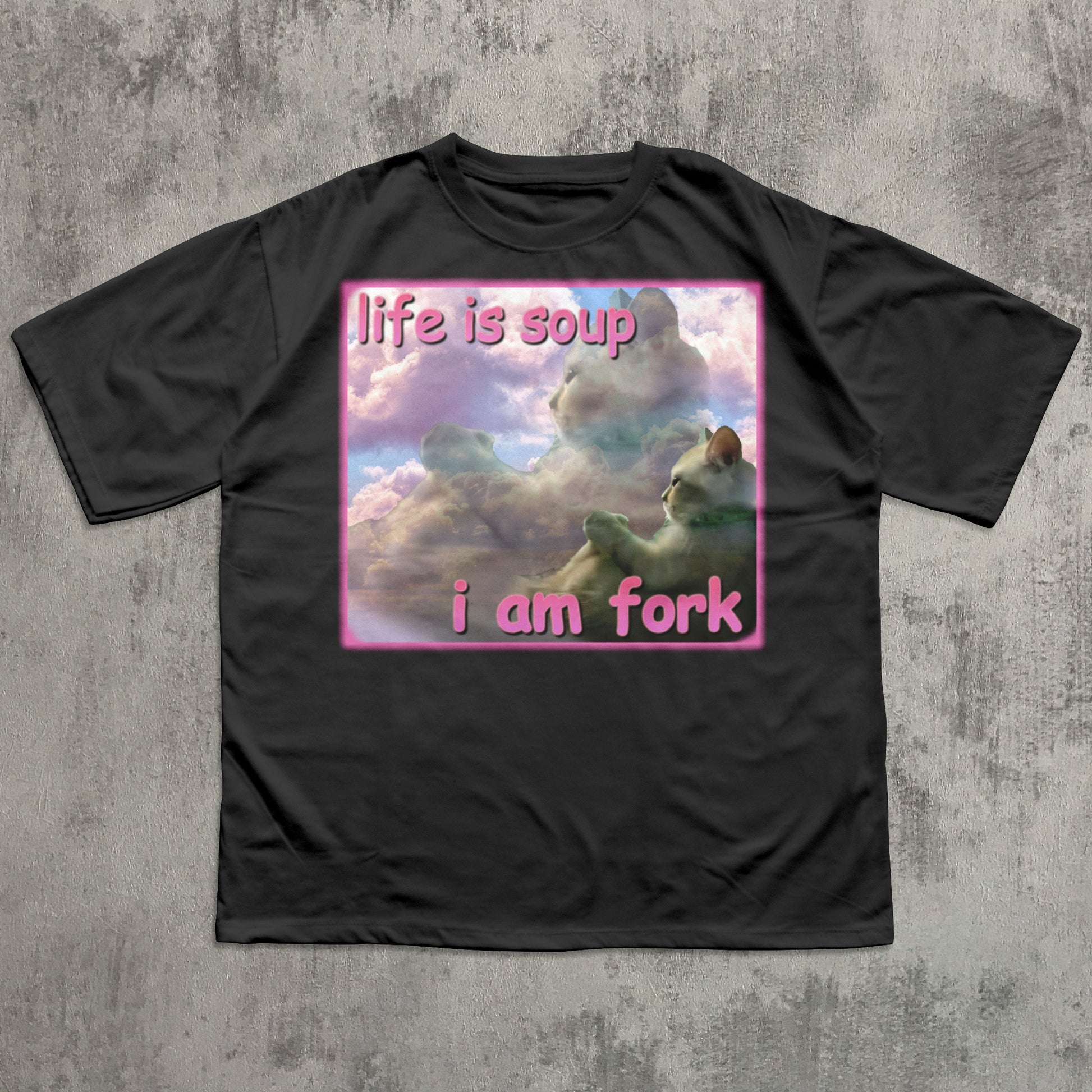 Black t-shirt with a graphic design of a cat in clouds and text 'life is soup i am fork' on a textured gray background.