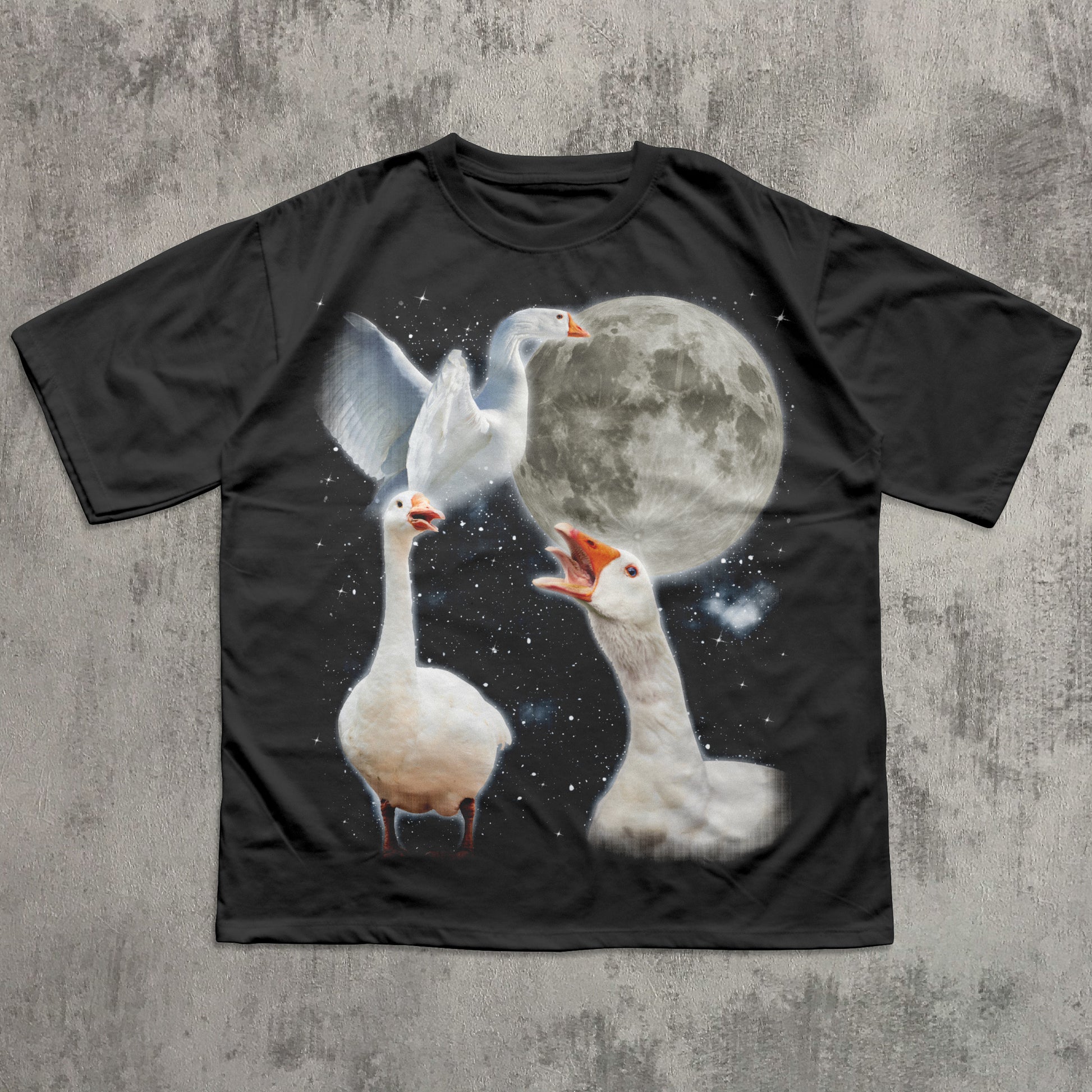 Black t-shirt with a graphic of three geese and a moon on a concrete surface