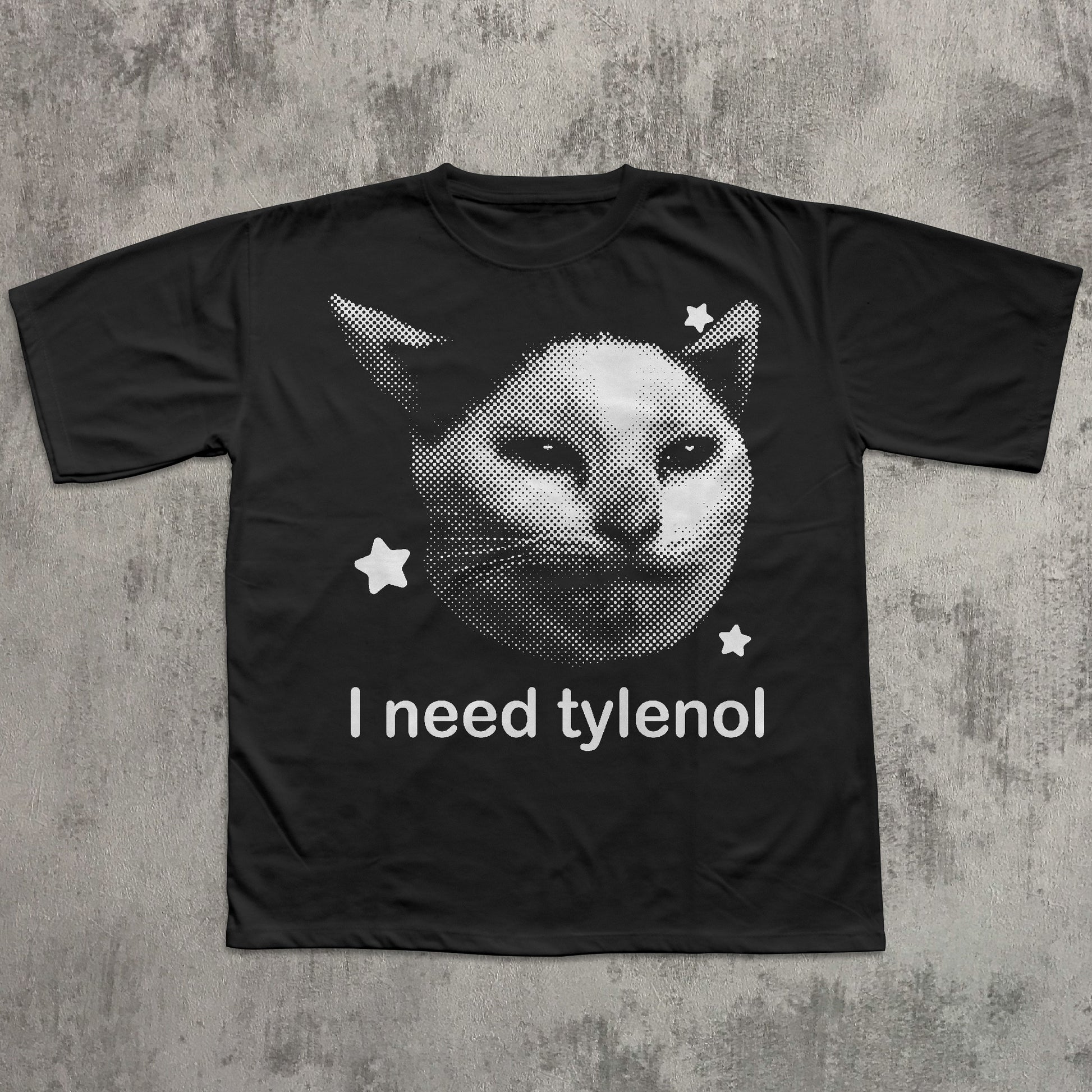 Black t-shirt with a cat graphic and 'I need tylenol' text on a textured gray background