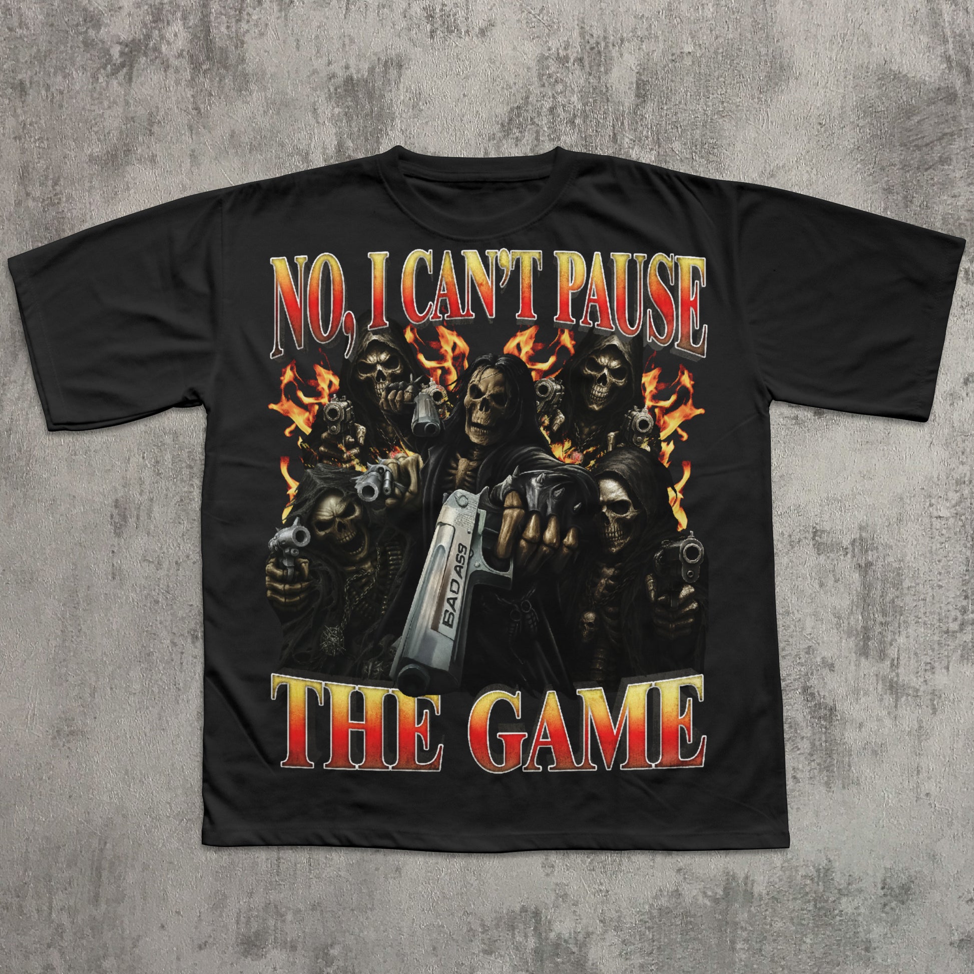 black t-shirt with graphic design of skeletons holding guns and a console, text 'No, I Can't Pause The Game' on a textured gray background.