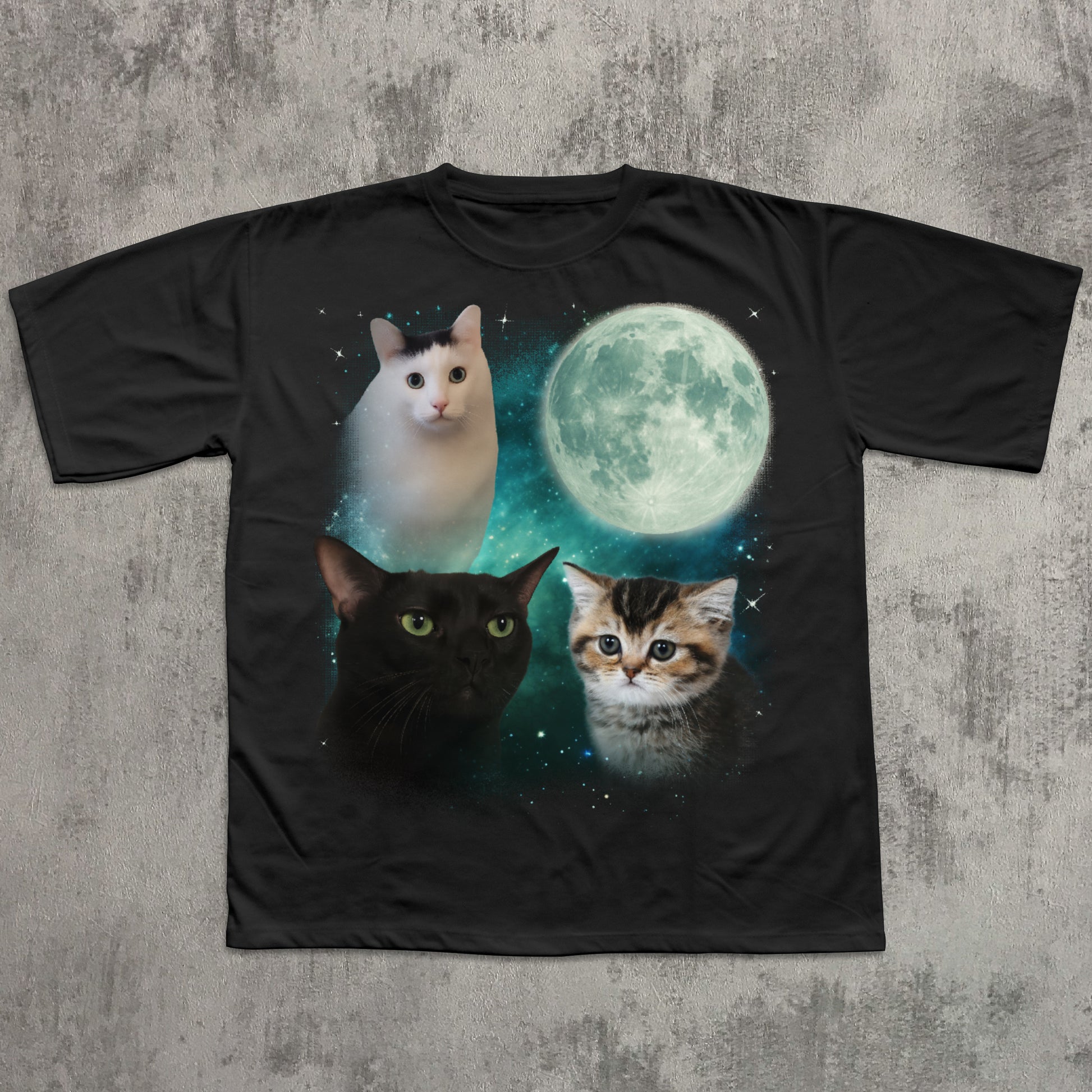 Black t-shirt with cats and a moon graphic on a textured gray background